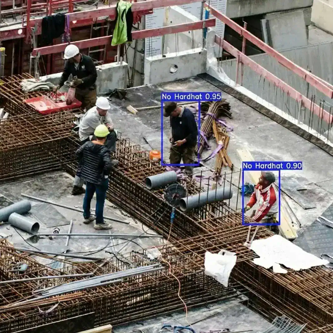Construction site camera view with AI boxes flagging two workers with no hard hat
