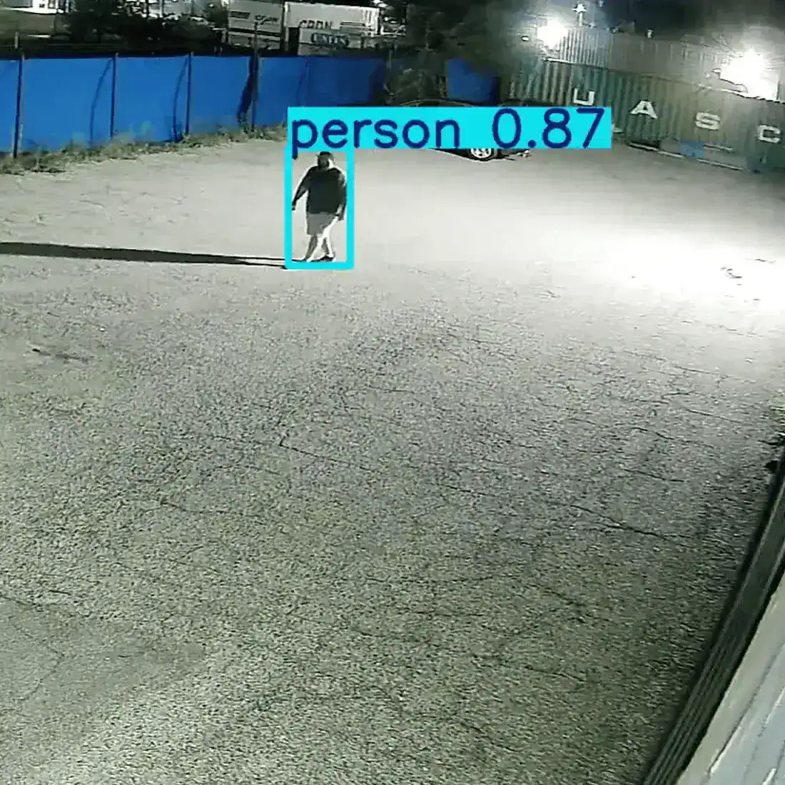 Night view of a gravel yard with a person walking inside a detection box labeled person 0.87