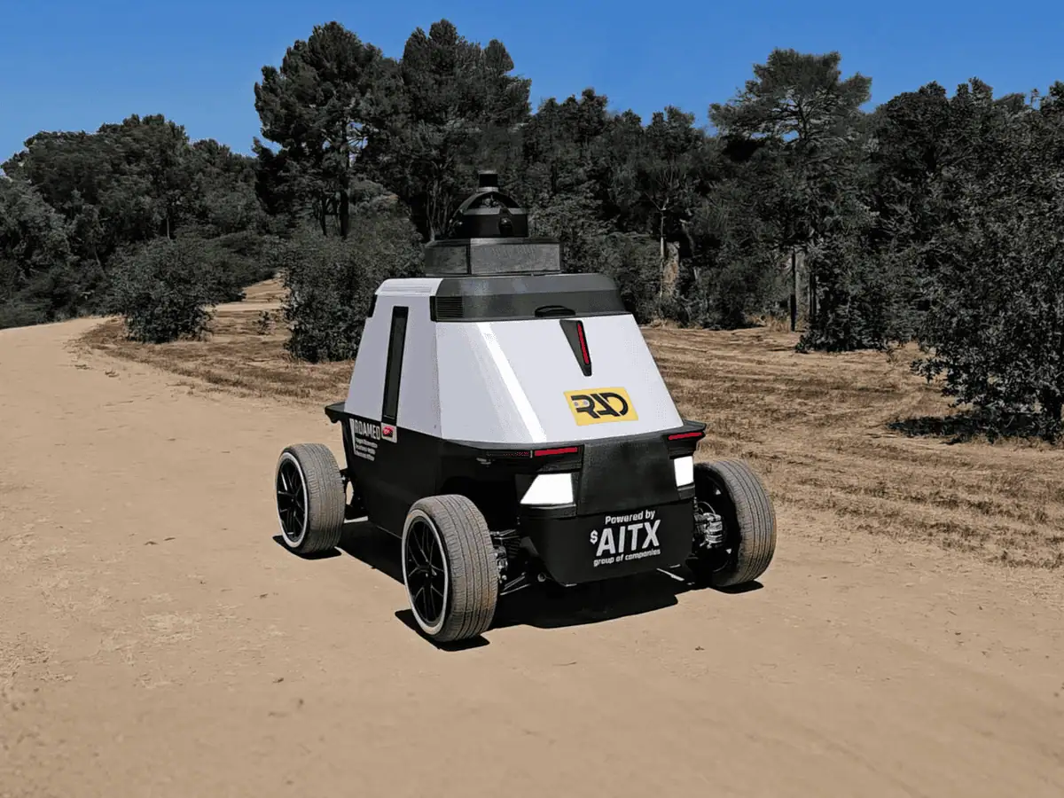 ROAMEO patrol robot on a dirt road through dry scrub and trees in daylight
