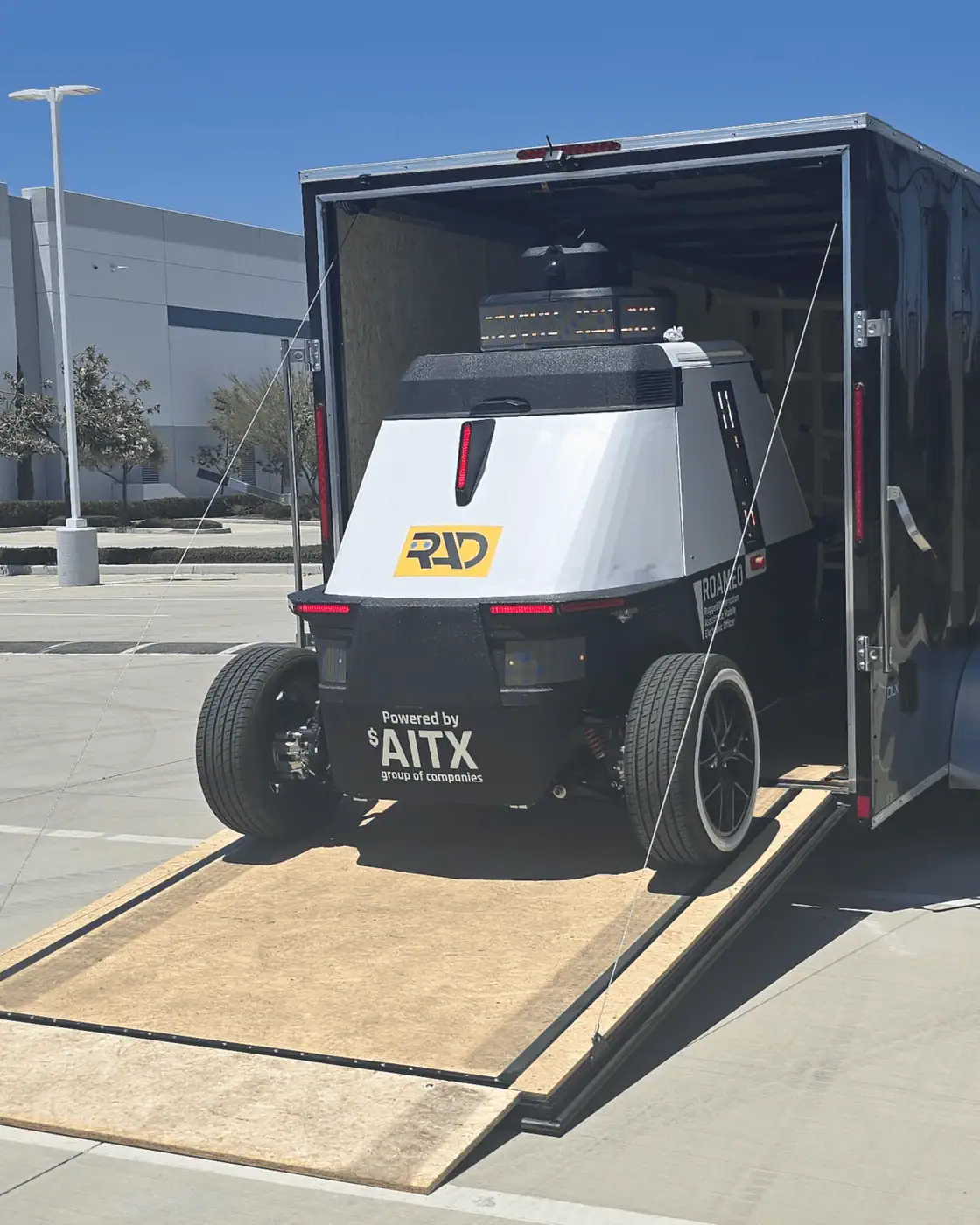 ROAMEO rolling down the ramp of an enclosed trailer onto a warehouse parking lot