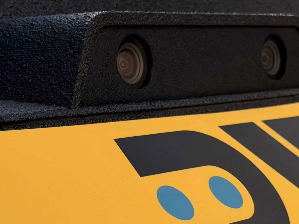 Close view of two camera lenses in a black housing above the yellow RAD badge on a ROAMEO body panel
