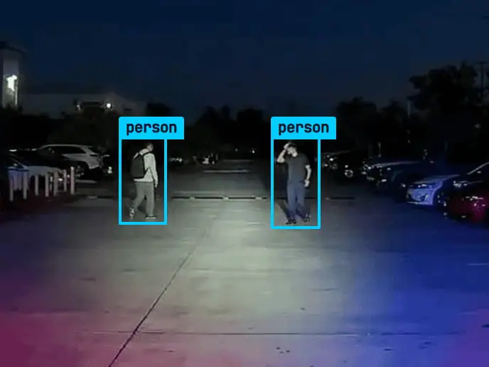 Night lot frame from a ROAMEO patrol camera with two people detected after hours