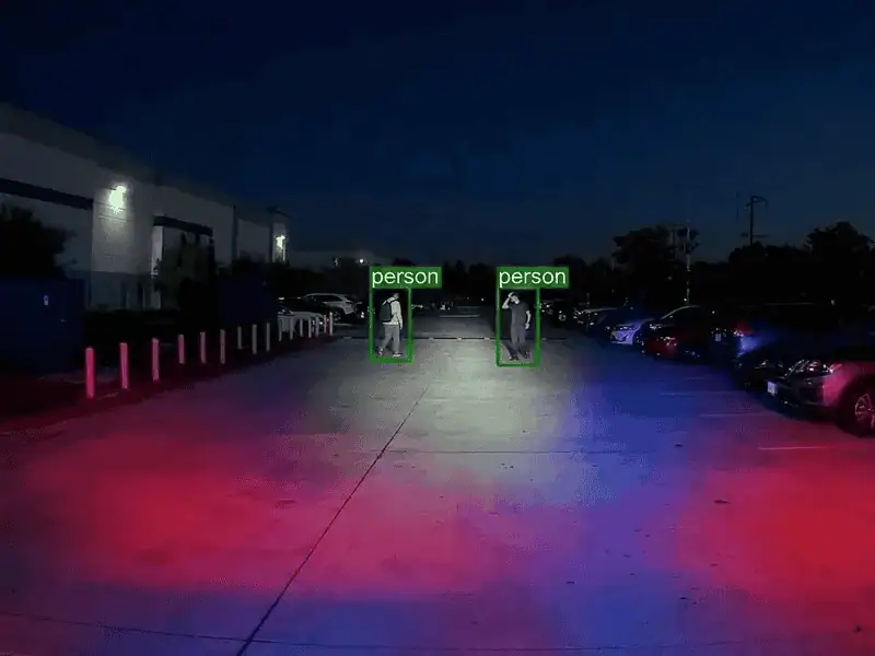 ROAMEO front-camera view of a parking lot at night with two people inside green person detection boxes