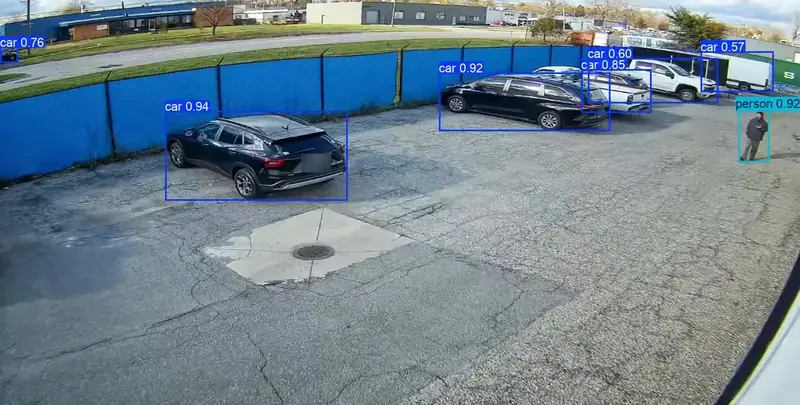 Daytime parking lot camera view with RAD AI analytics boxes on cars and a person