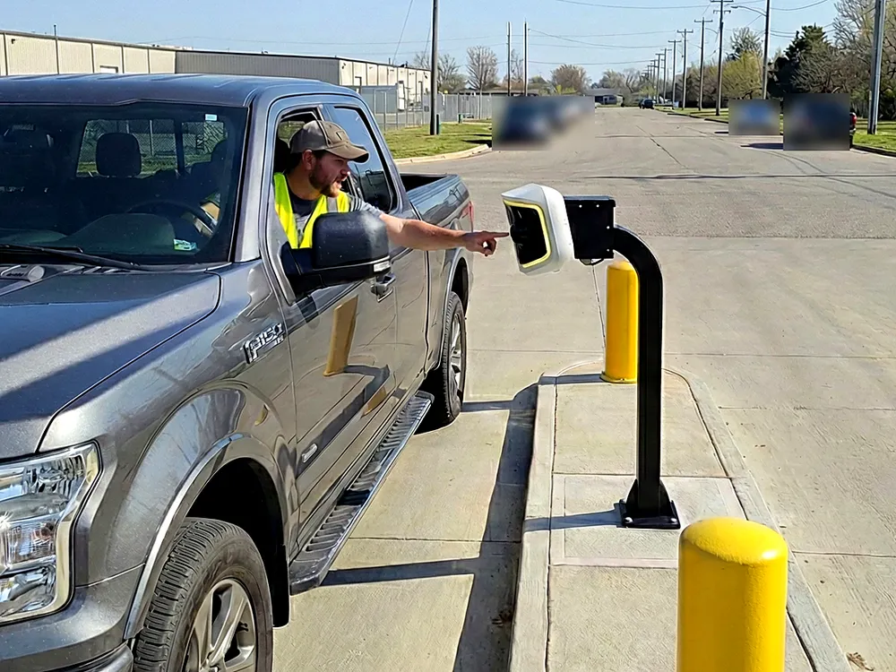 A driver reaches from a pickup to an AVA unit in a gate lane