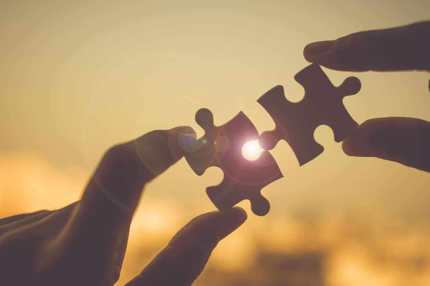 Dos manos juntando piezas de un puzzle