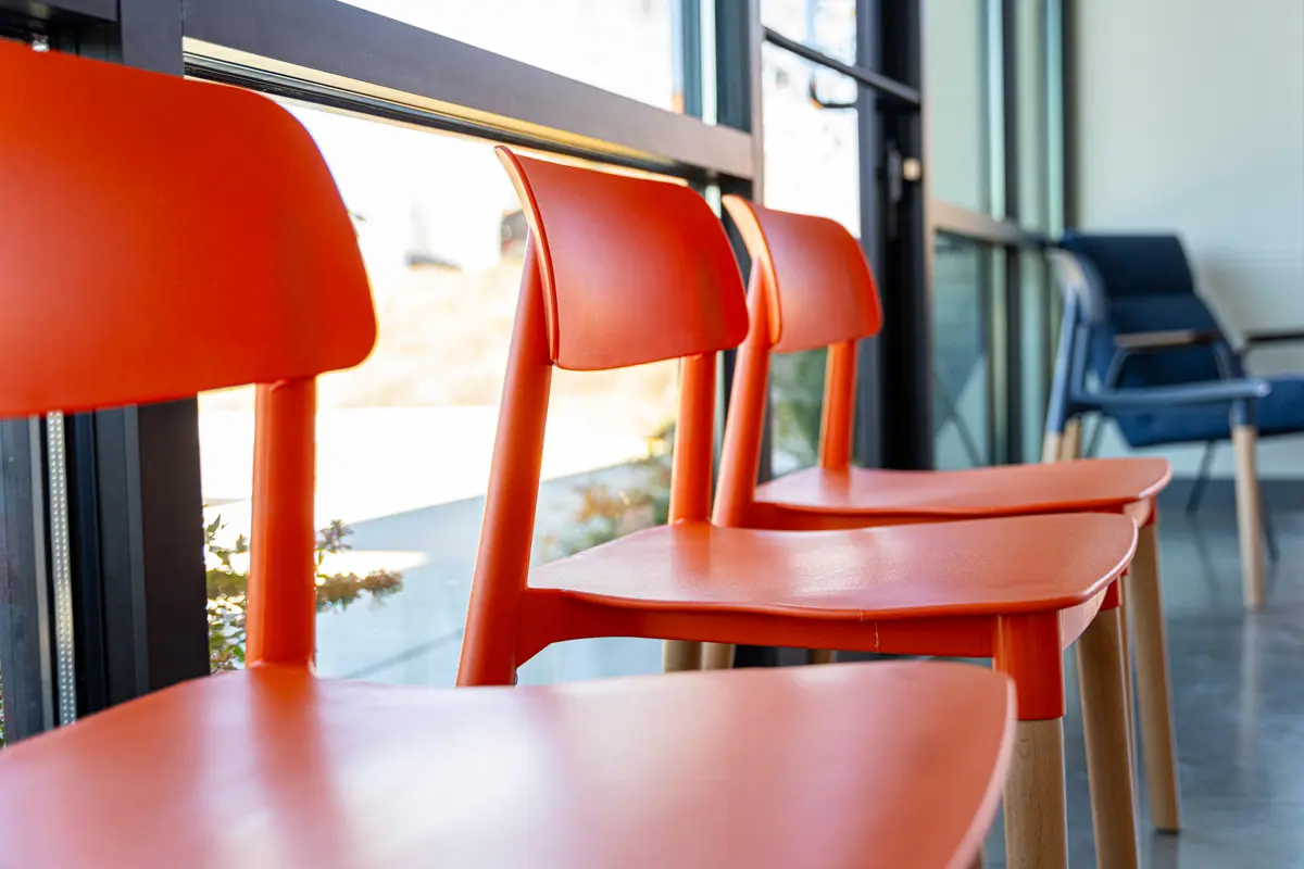 a row of orange chairs sitting next to a window