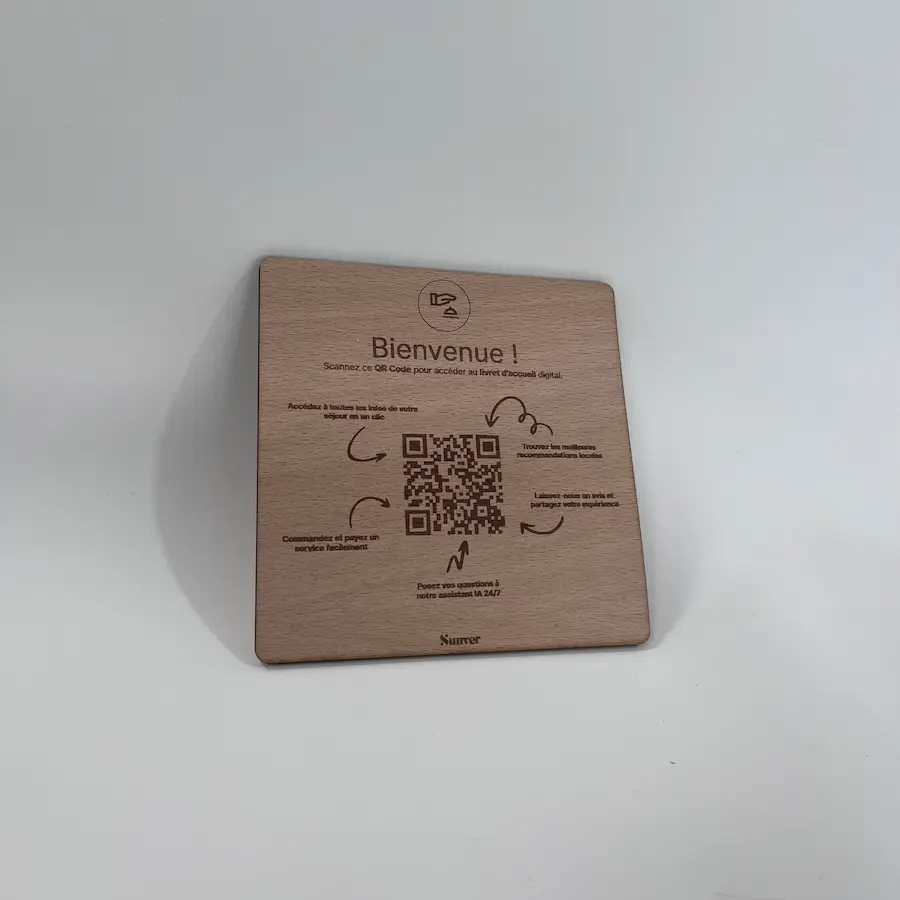 Photo of a square wooden QR code plate on a desk.