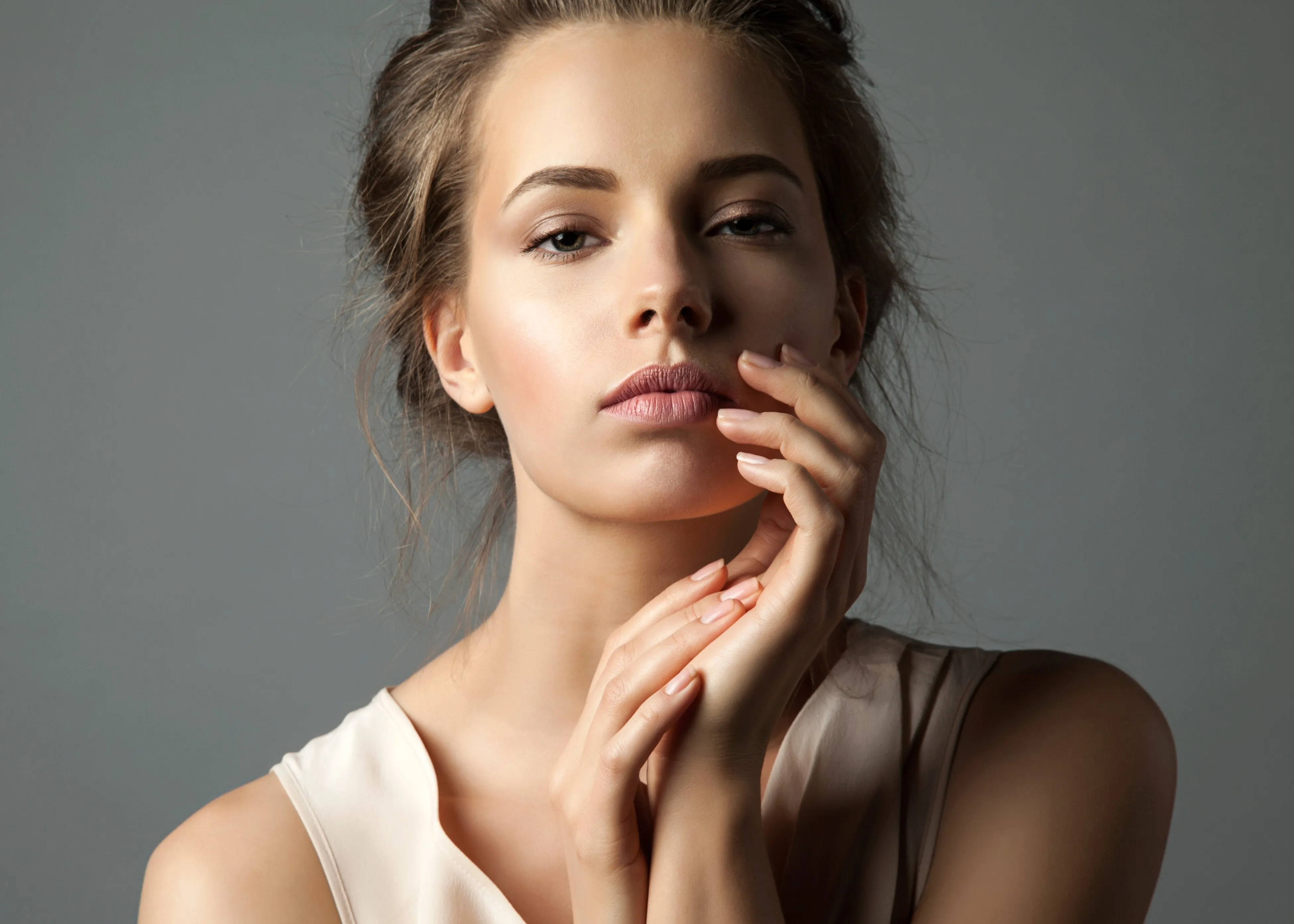A woman smiling touching her face