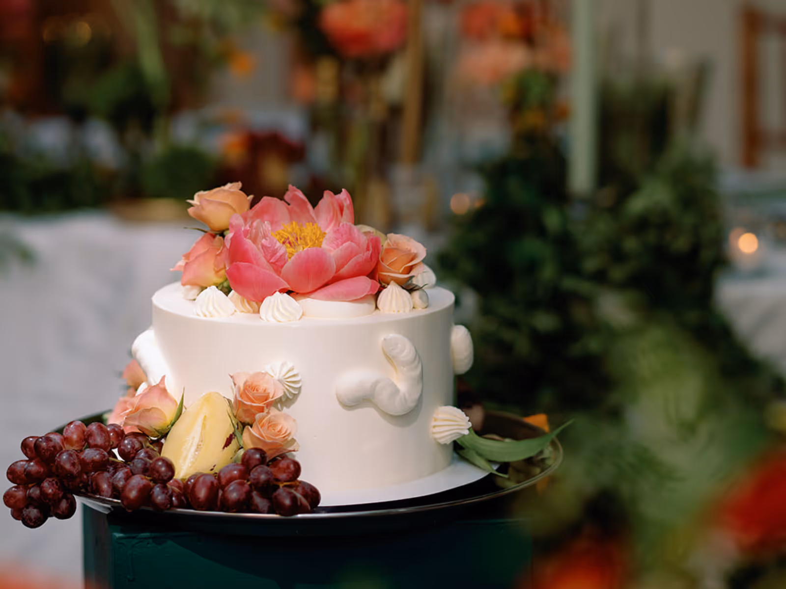 White cake decorated with flowers and grapes on a table