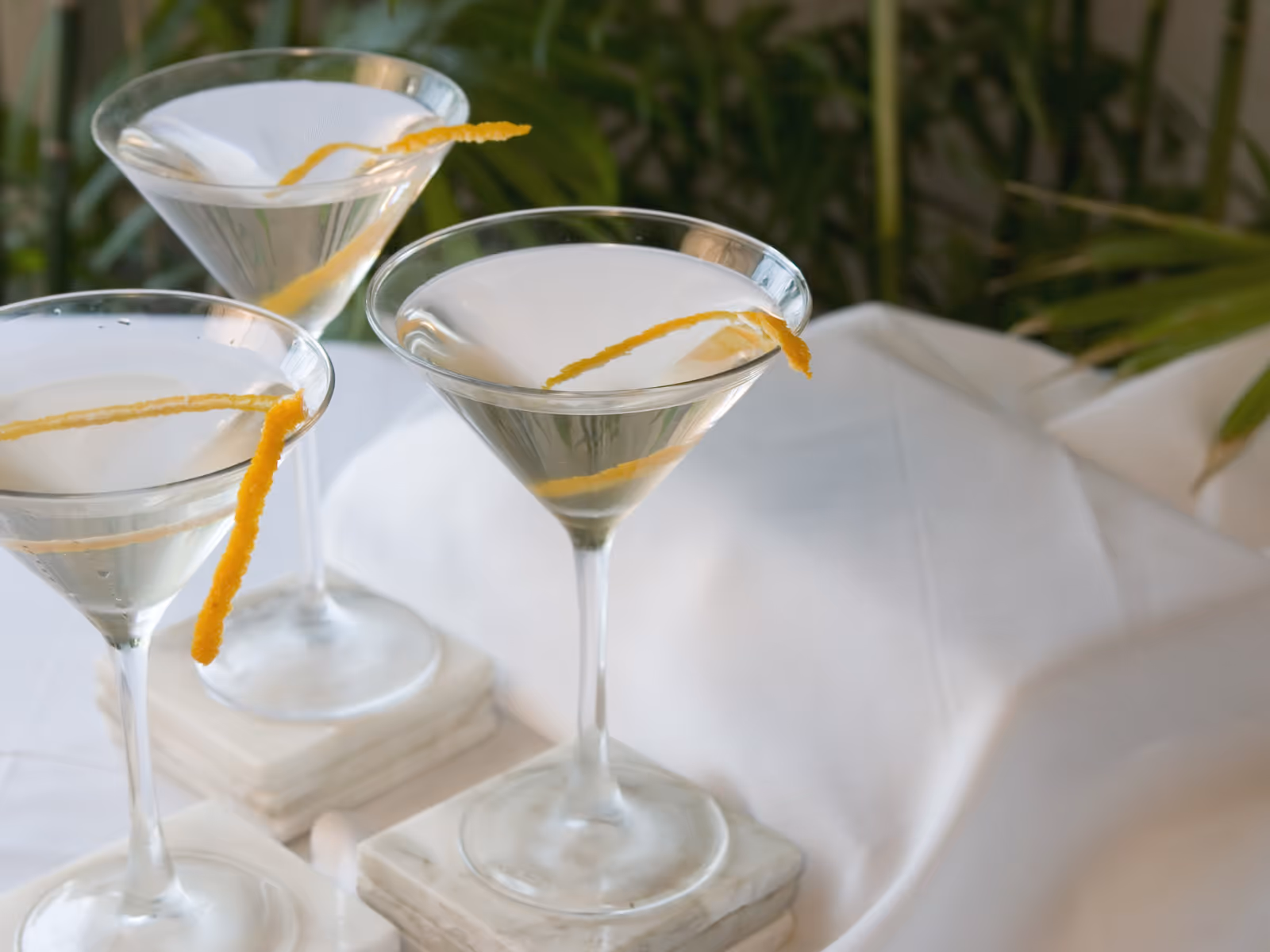 Two martini glasses with a lemon twist on a white tablecloth