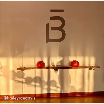Mujer con cabello rizado con ropa deportiva de color óxido realizando una sentadilla con una banda de resistencia alrededor de sus muslos.