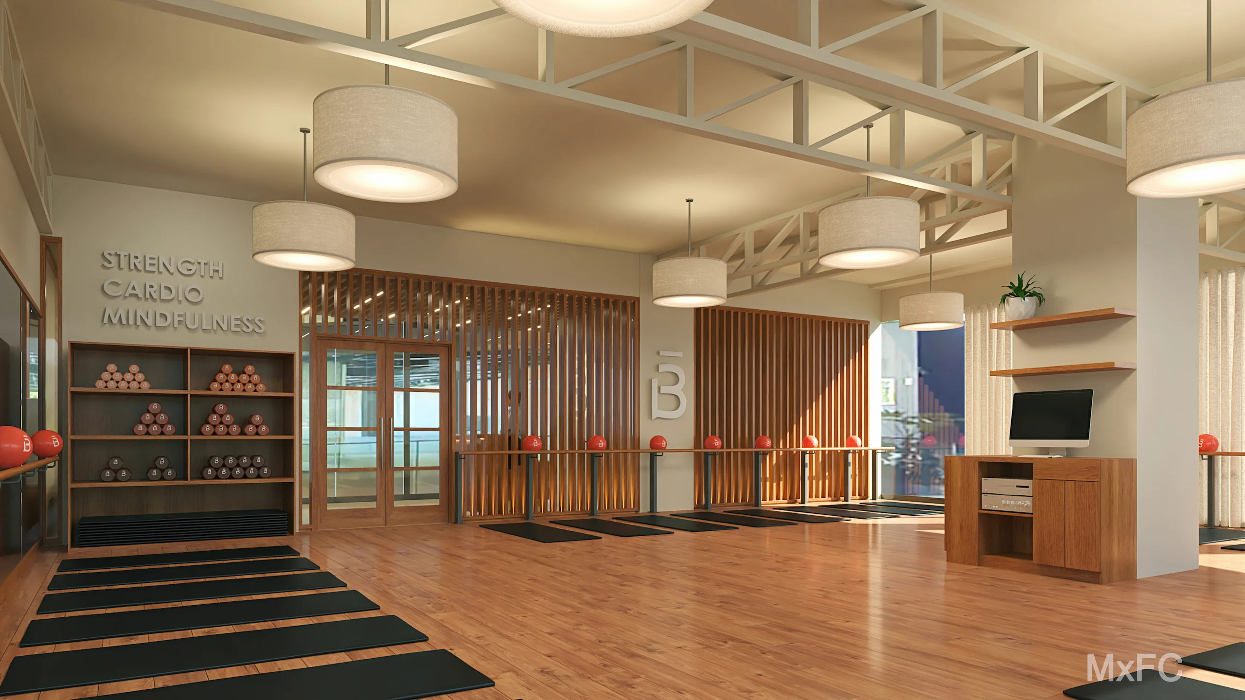 Amplio estudio barre3 Santiago con suelos de madera, colchonetas de ejercicio negras, balones medicinales rojos, luces de techo redondas y las palabras 'Strength Cardio Mindfulness' en la pared.