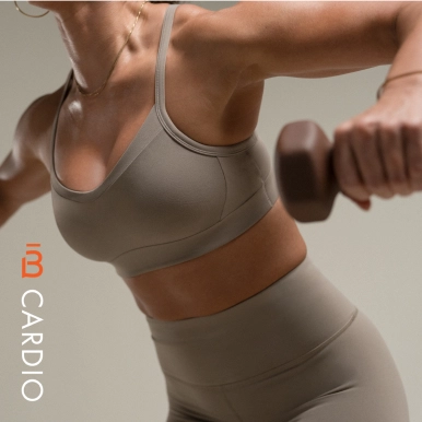 Primer plano de una mujer vestida con ropa deportiva gris realizando un ejercicio con mancuernas sobre un fondo neutro en barre3 Santiago.