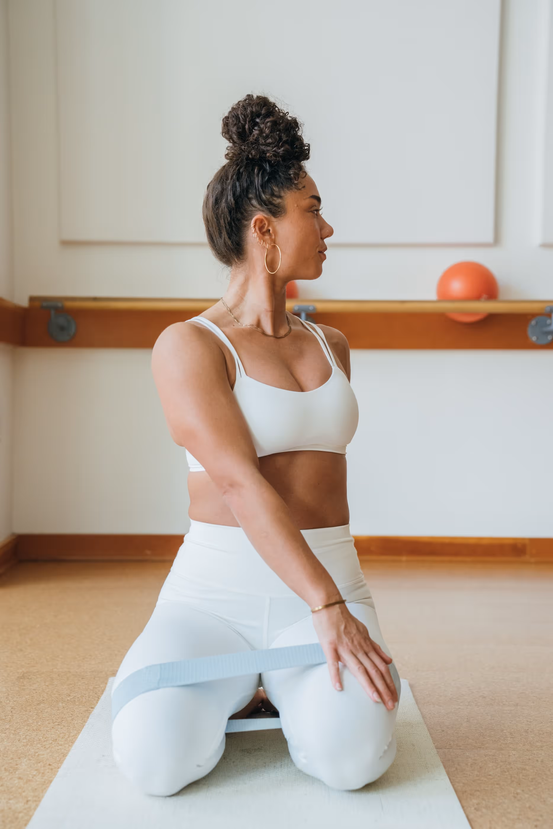 Mujeres vestidas con ropa deportiva realizando un ejercicio de levantamiento de piernas de pie con bandas de resistencia en un luminoso estudio de fitness barre3 Santiago.