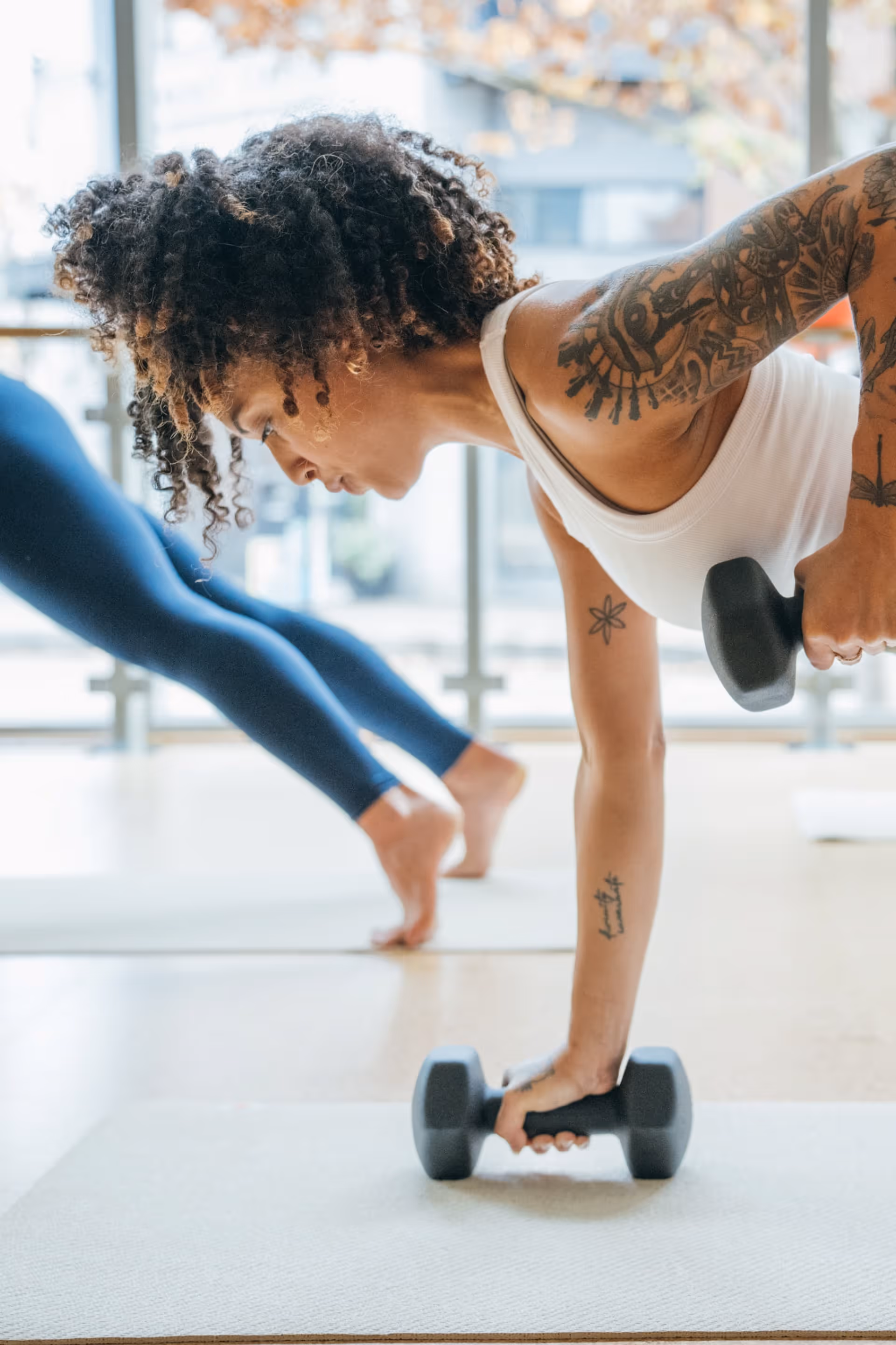 Primer plano de una mujer con un sujetador deportivo marrón estirándose en una clse de barre3 Santiago.