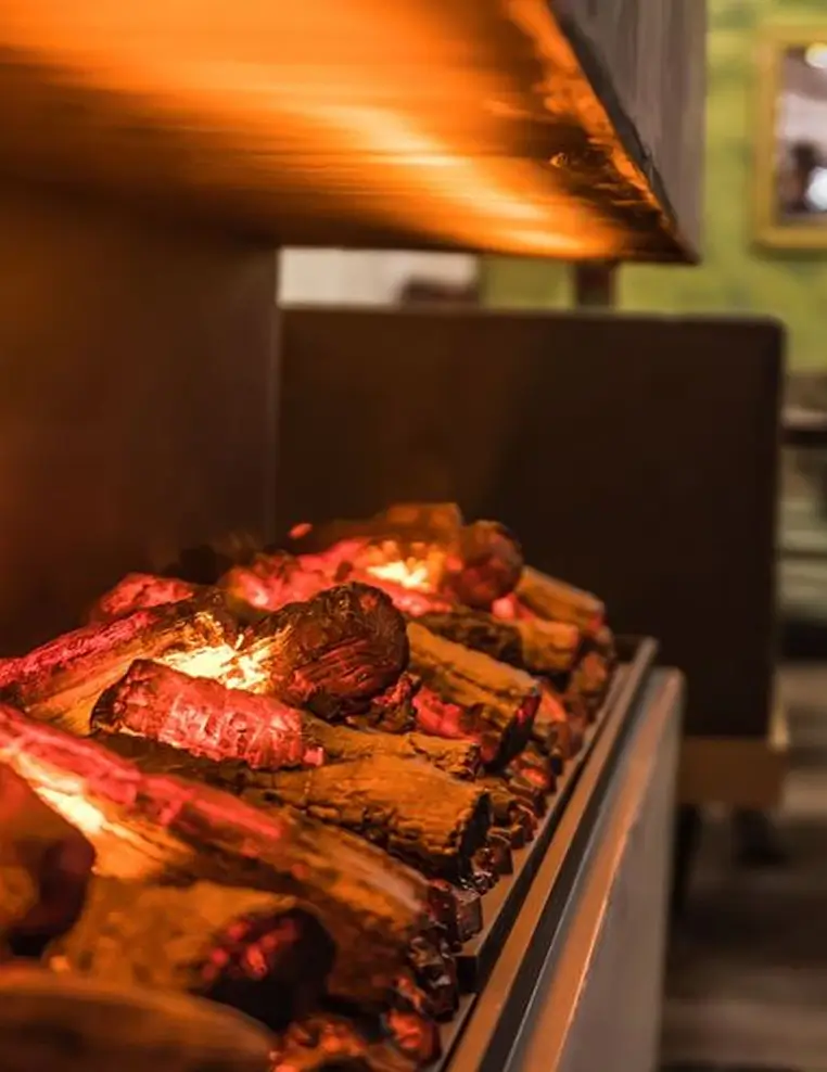 Close-up of glowing firewood logs burning inside a modern indoor fireplace.