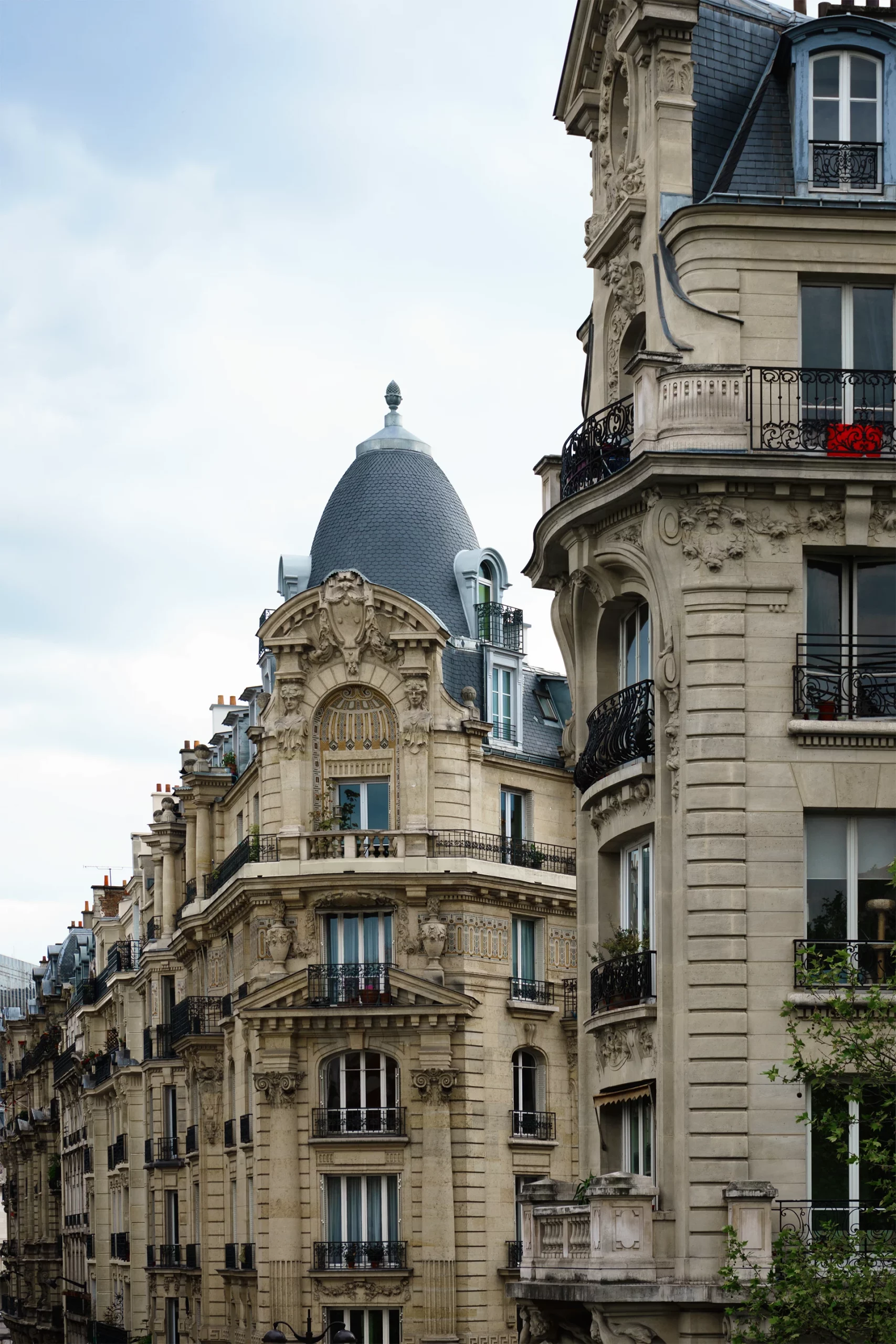 Façade d'immeubles haussmanniens avec balcons en fer forgé et toits en ardoise en forme de dôme à Paris.