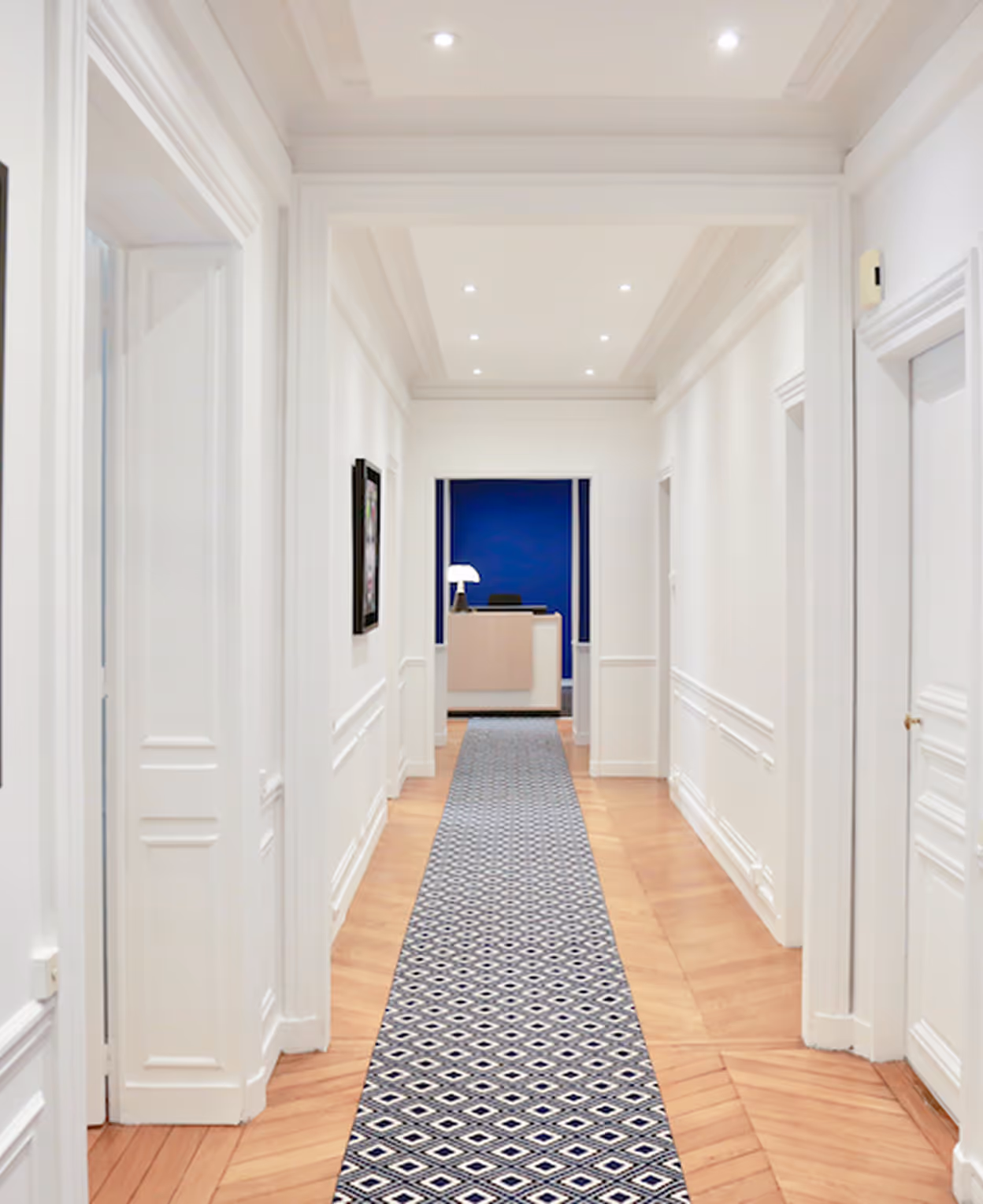 Un groupe de cinq professionnels souriants portant des costumes formels posant devant un fond bleu.