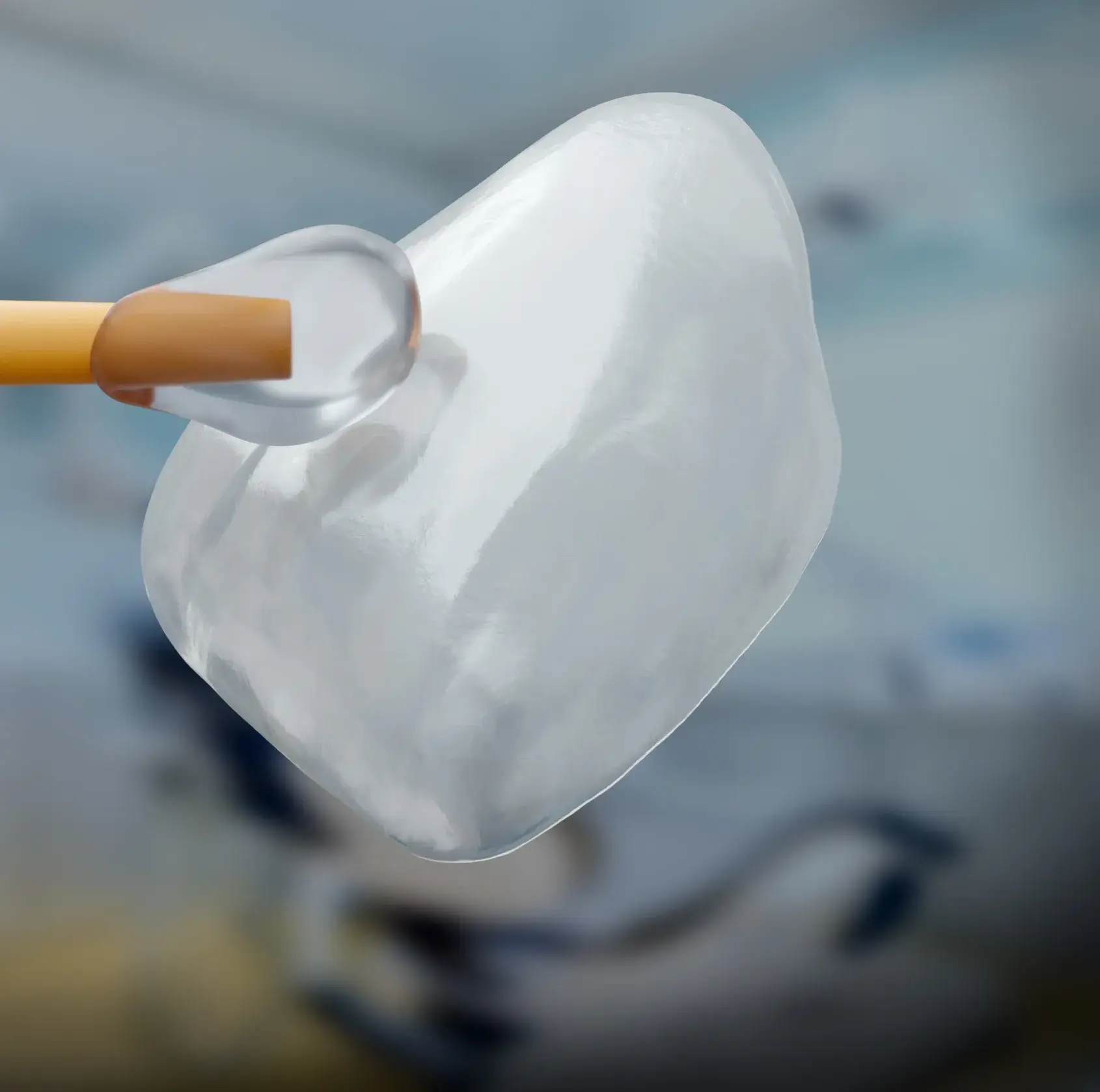 Close-up of dental veneer being held by a tool against a blurred background.