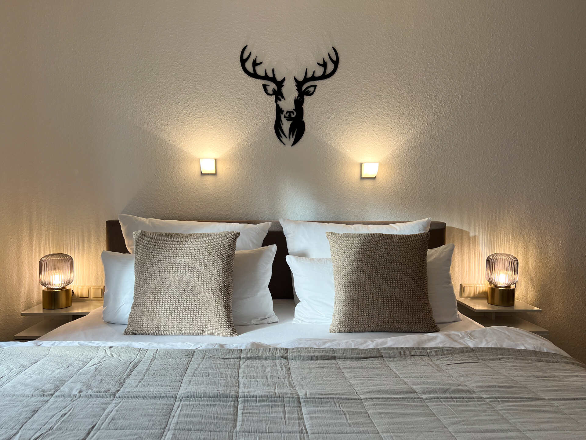 Doppelbett mit Hirschdeko und Nachttischlampen