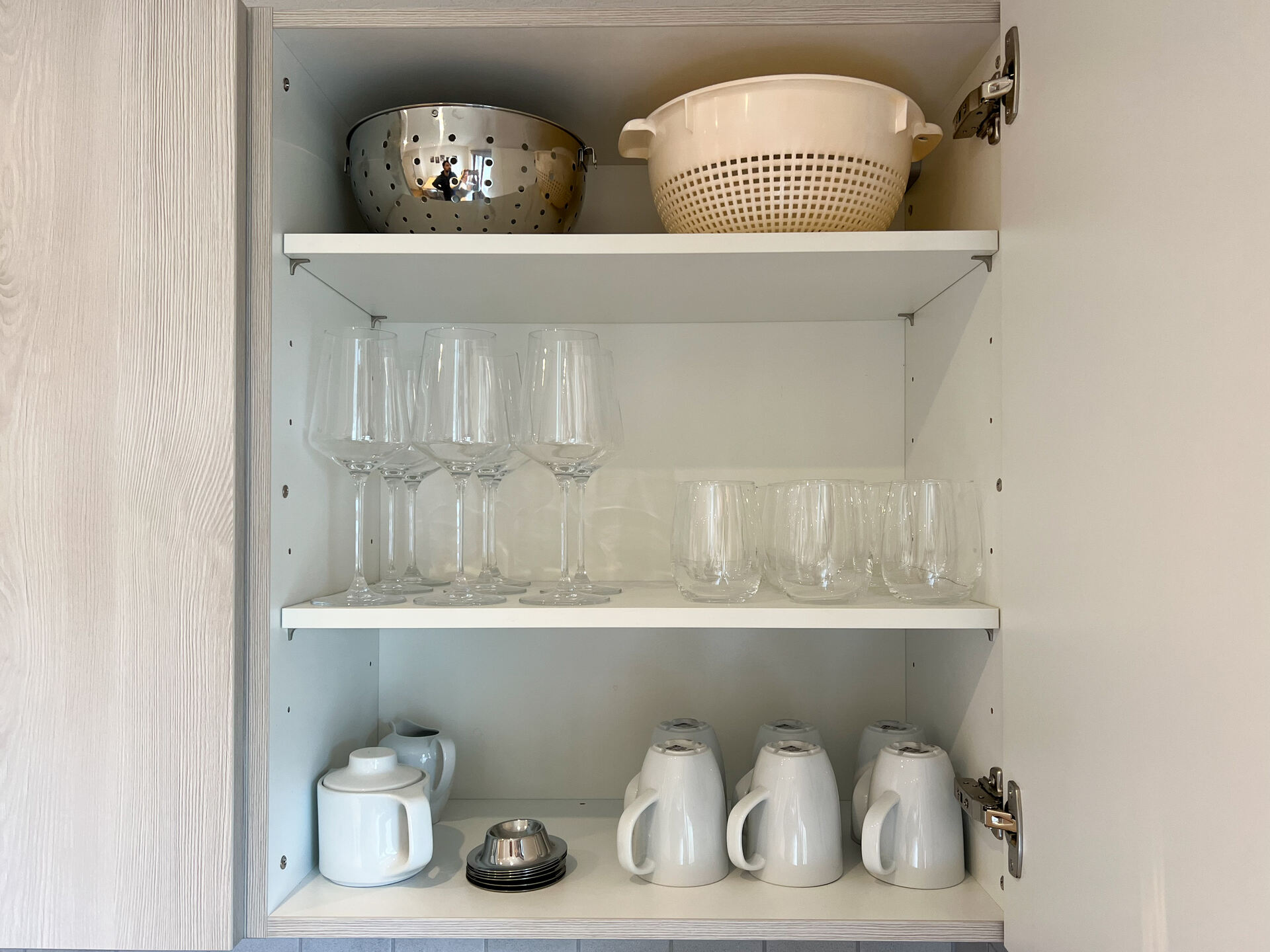 Kuechenschrank mit Glaesern, Tassen und Sieben