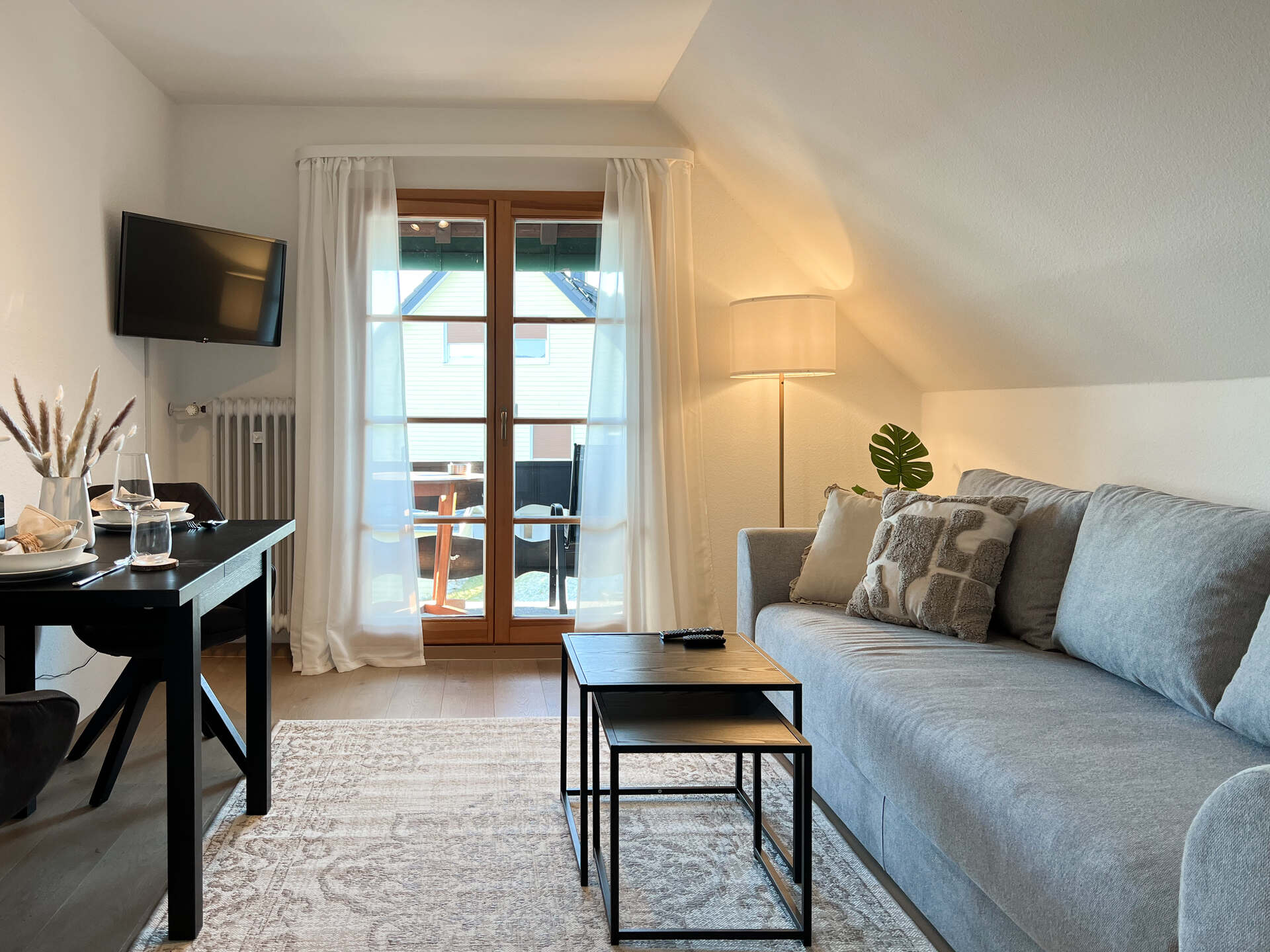 Wohnzimmer mit Sofa, TV und Zugang zum Balkon