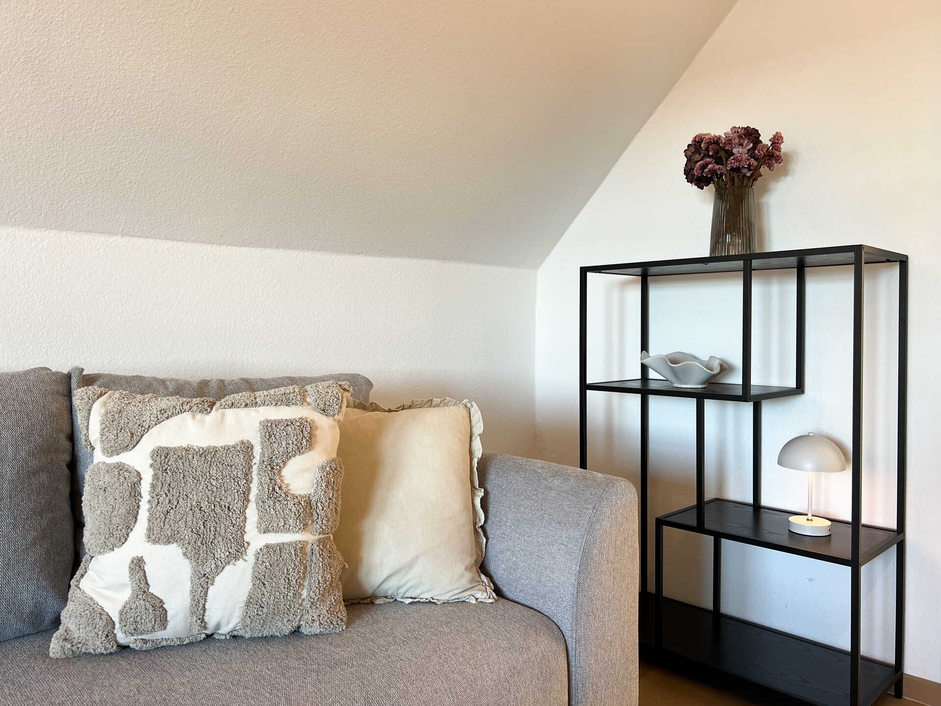 Couch mit Dekokissen und schwarzem Regal