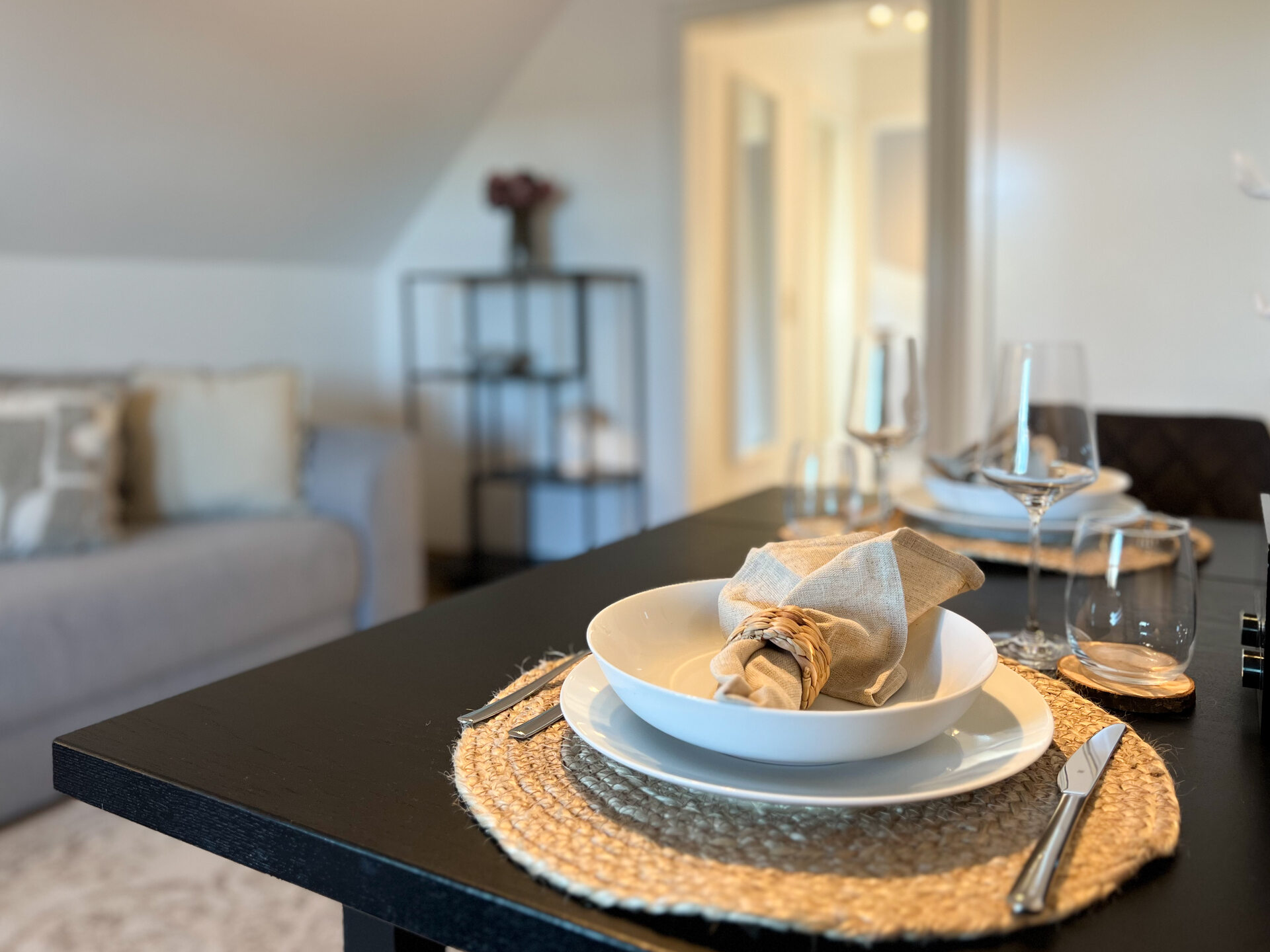 Esstisch mit Gedeck vor Couch und Regal