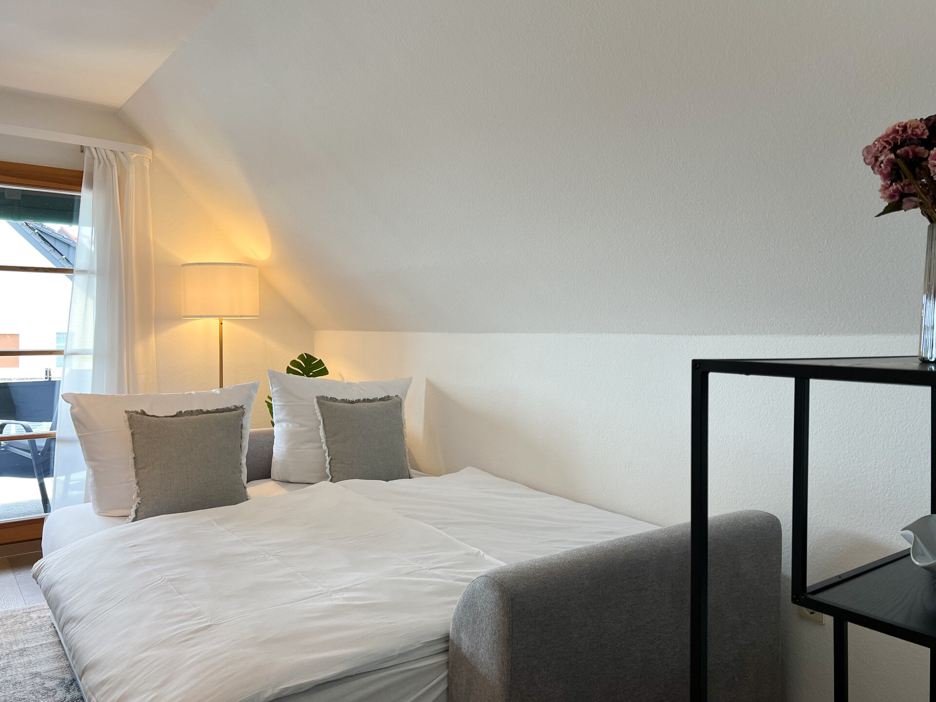 Schlafsofa mit Kissen neben Regal und Lampe