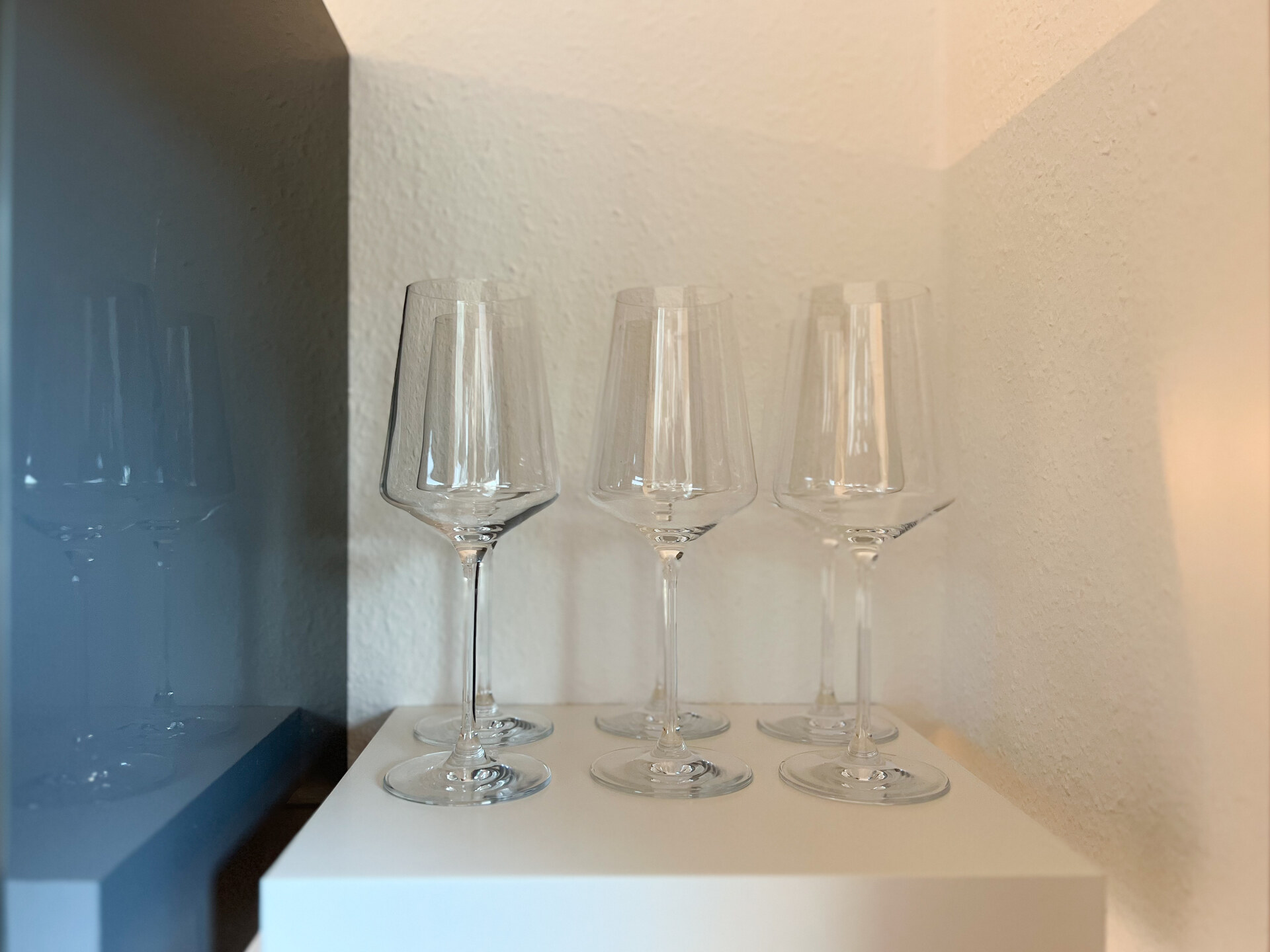 Sechs Weinglaeser auf weissem Regal