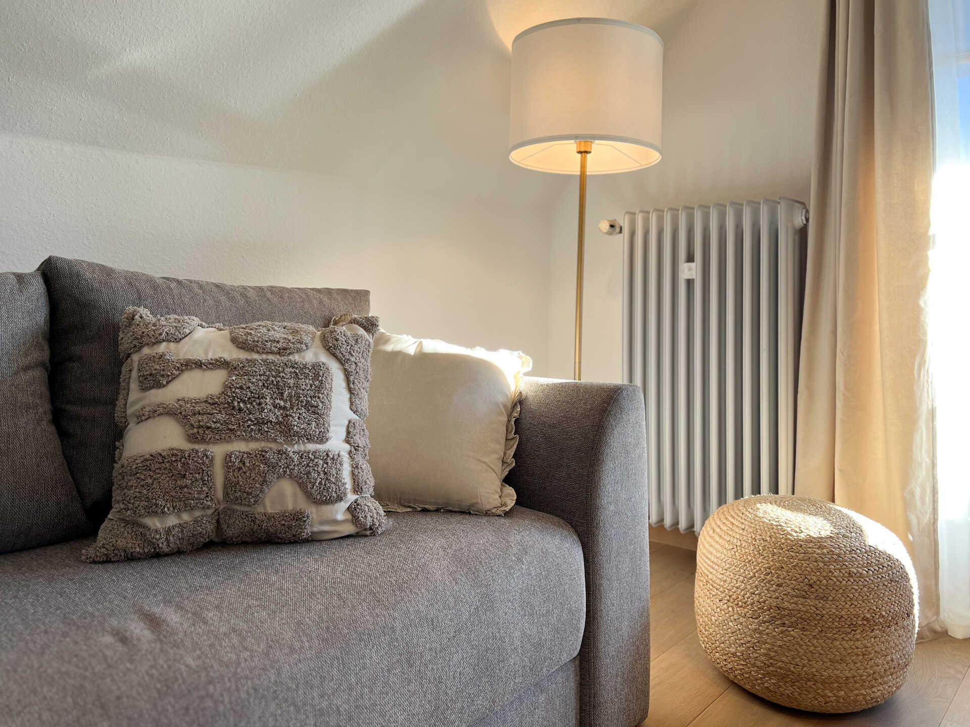 Sofa mit Kissen, Stehlampe und Pouf