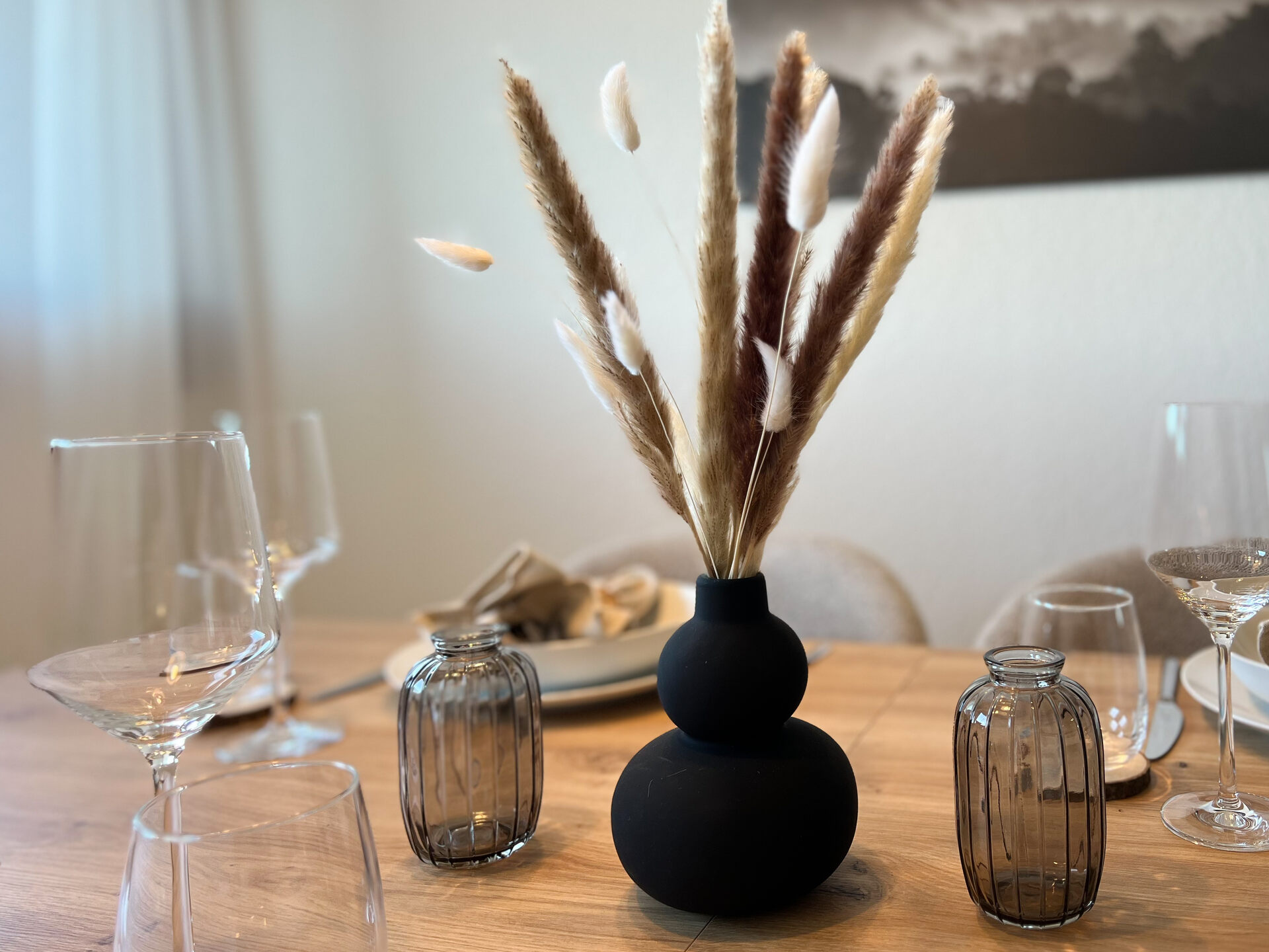 Vase mit Trockenblumen auf gedecktem Esstisch