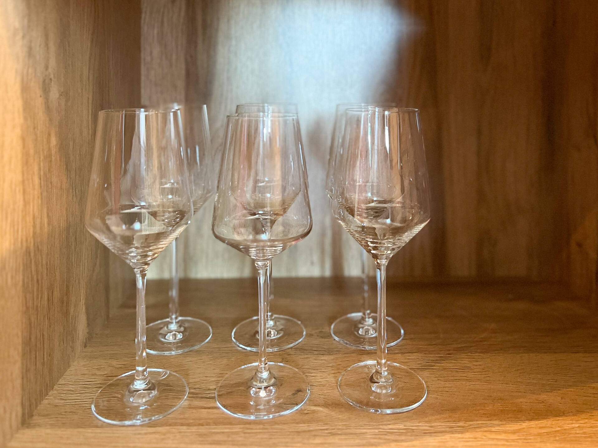 Sechs Weinglaeser in einem Holzregal