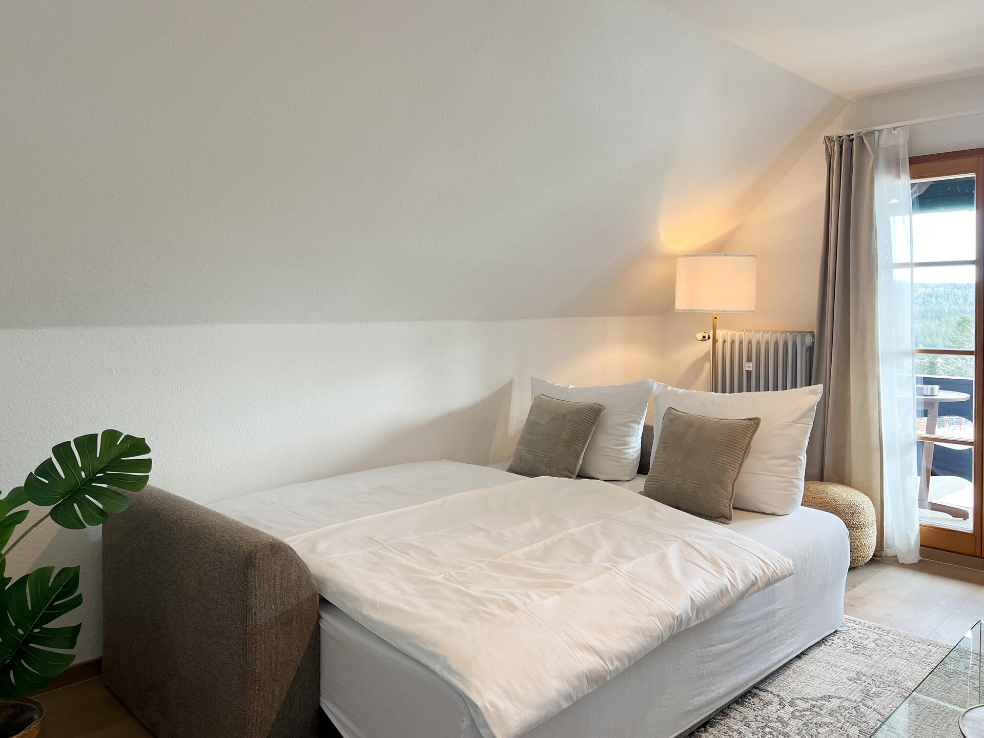 Schlafsofa mit Kissen neben Fensterfront