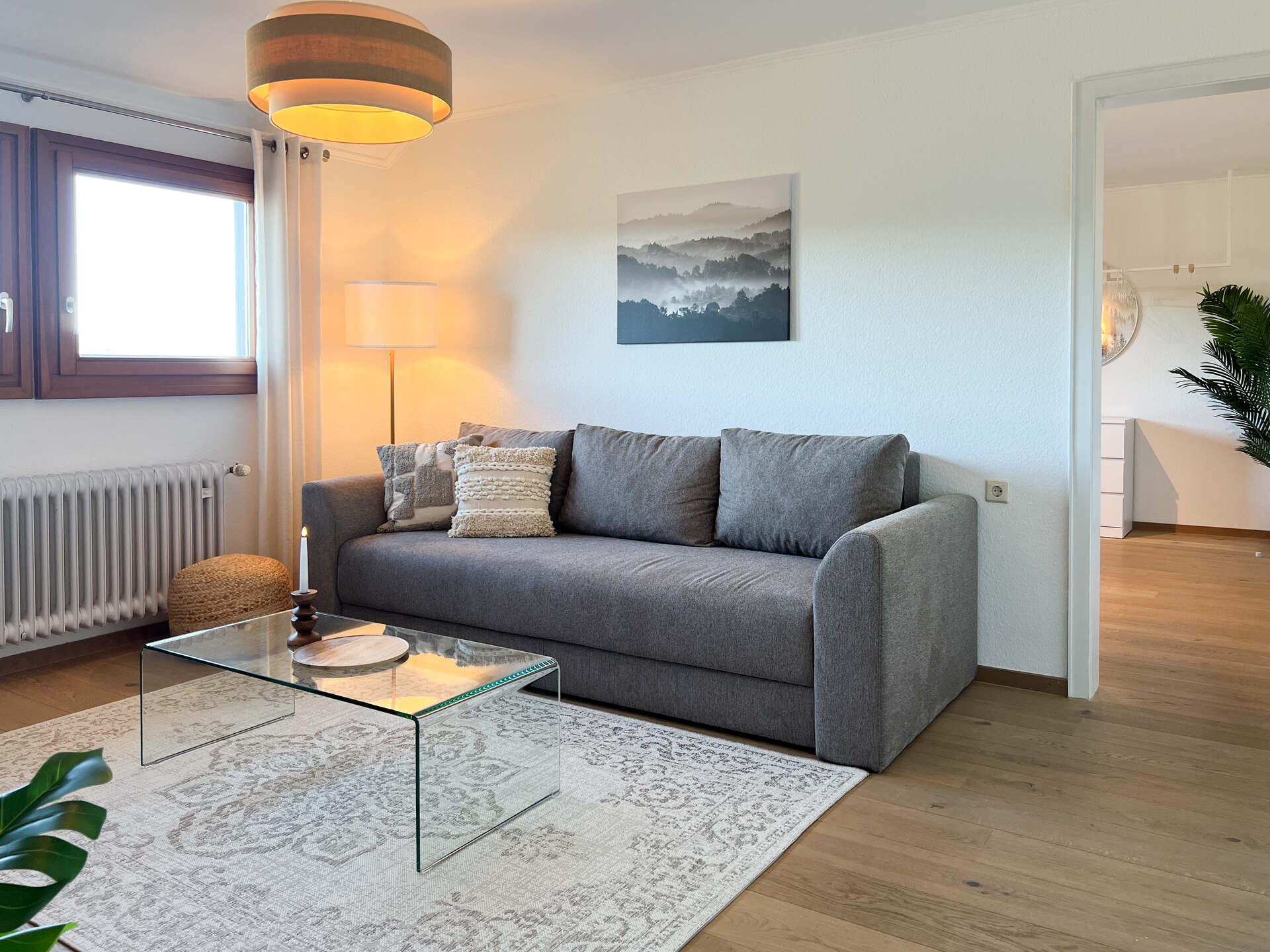 Graues Sofa mit Glastisch und Stehlampe im Wohnzimmer