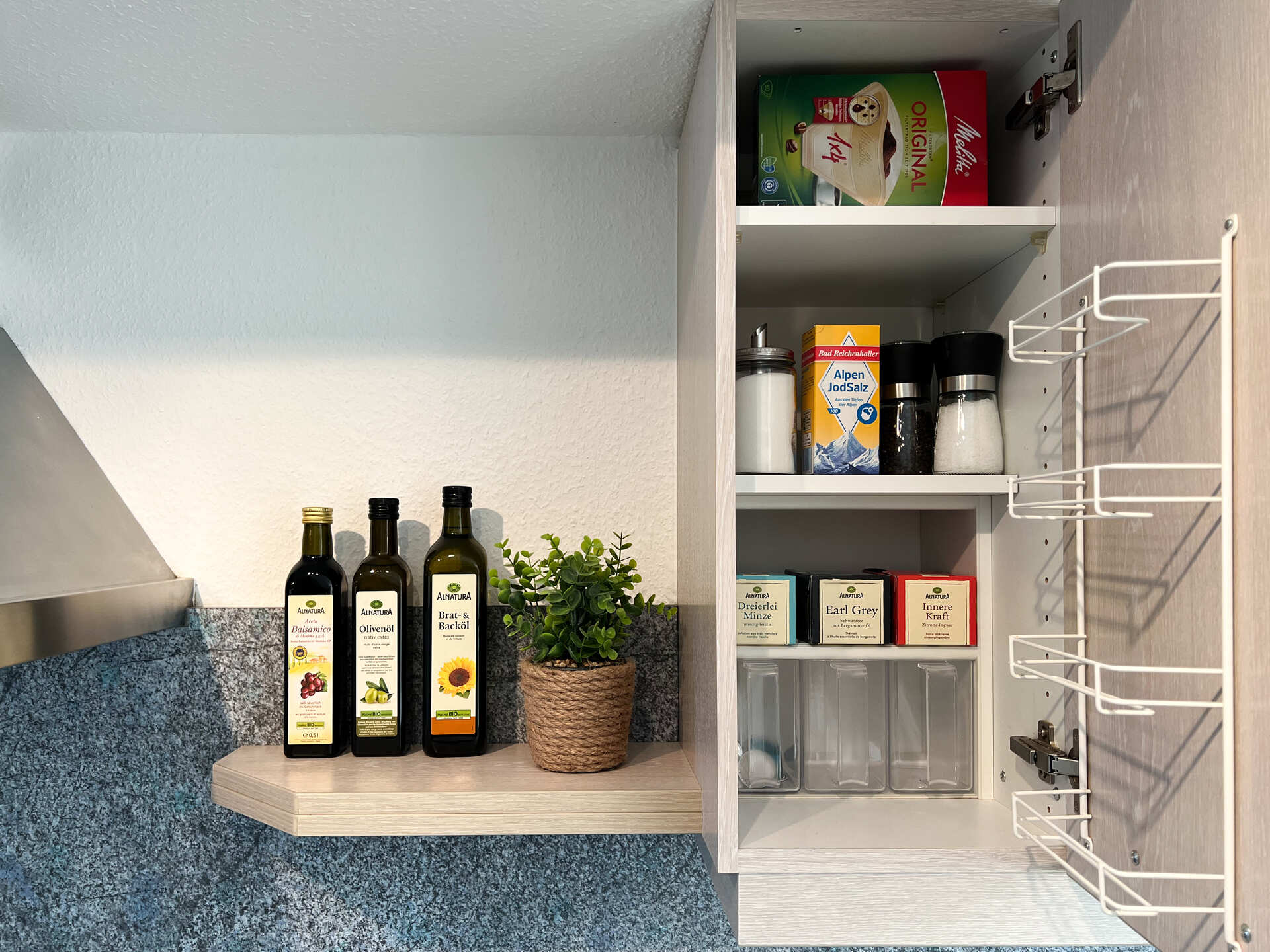 Kuechenschrank mit Oelflaschen, Gewuerzen und Teesorten