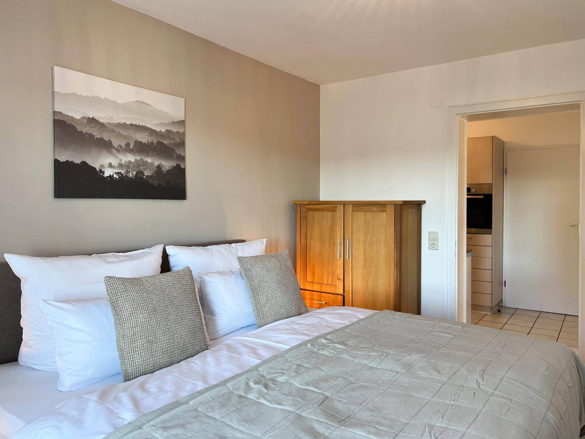 Schlafzimmer mit Holzmoebeln und Tuer zur Kueche