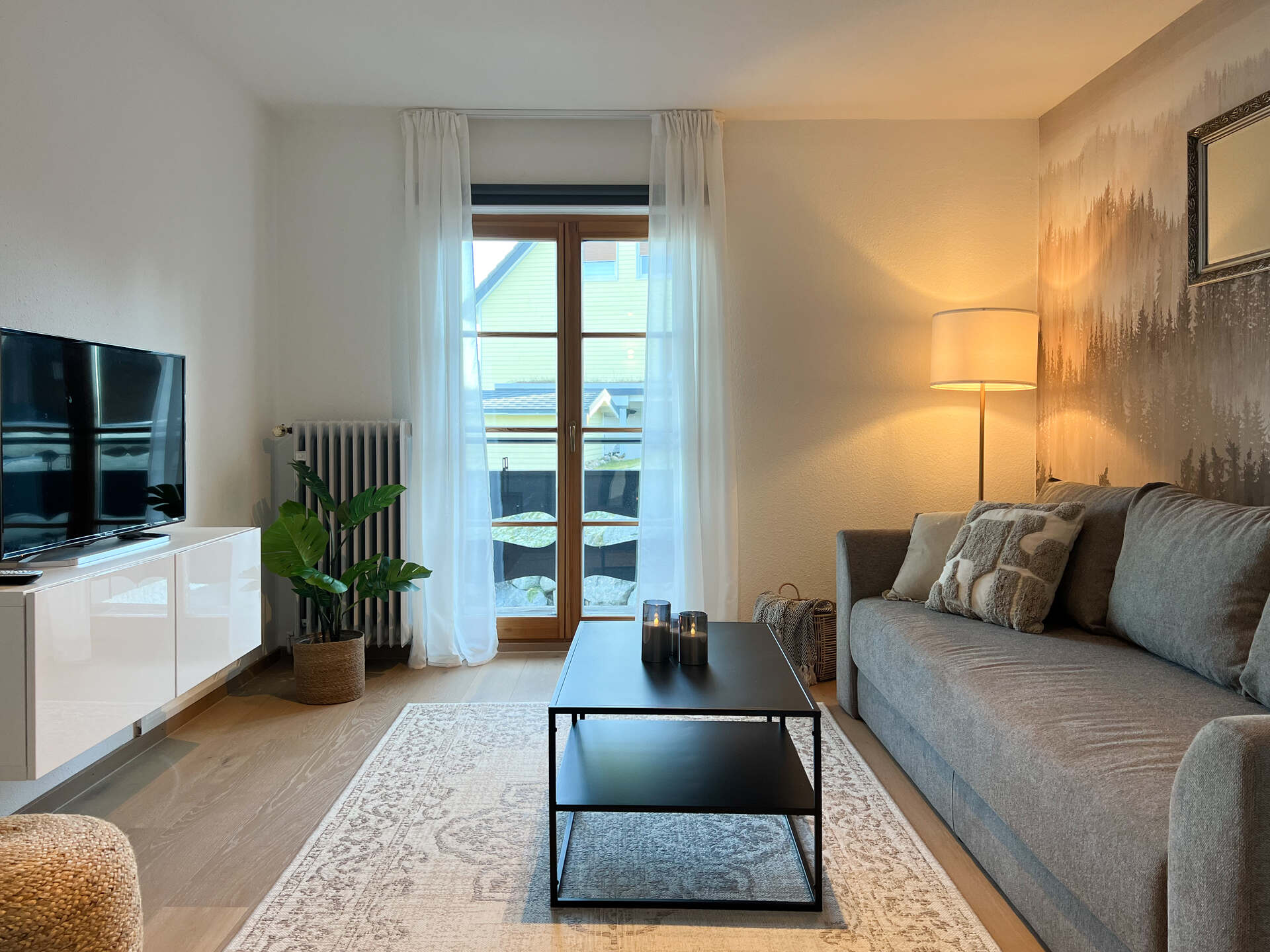 Wohnzimmer mit Sofa, TV und Balkonzugang