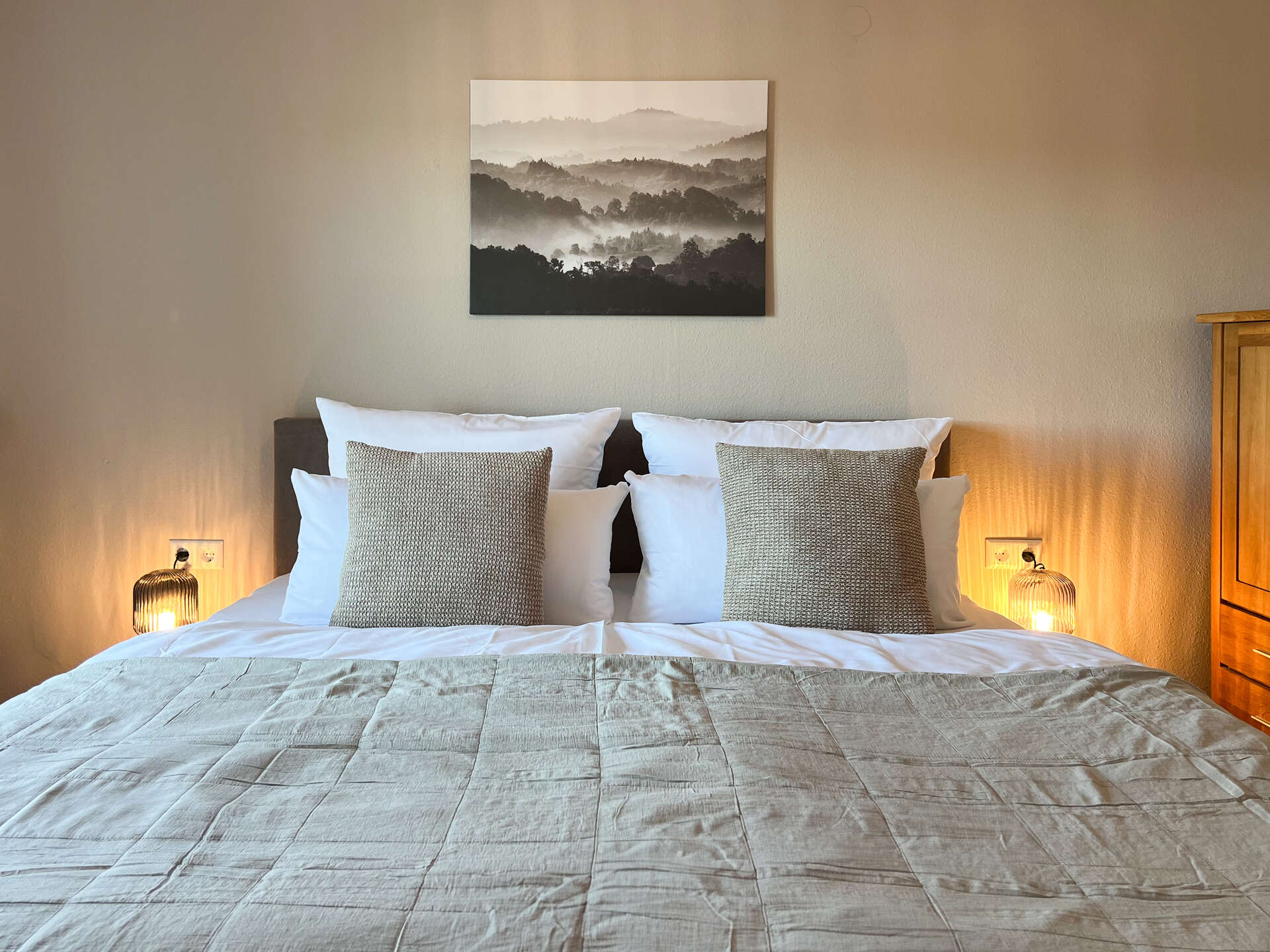 Doppelbett mit Landschaftsbild an der Wand