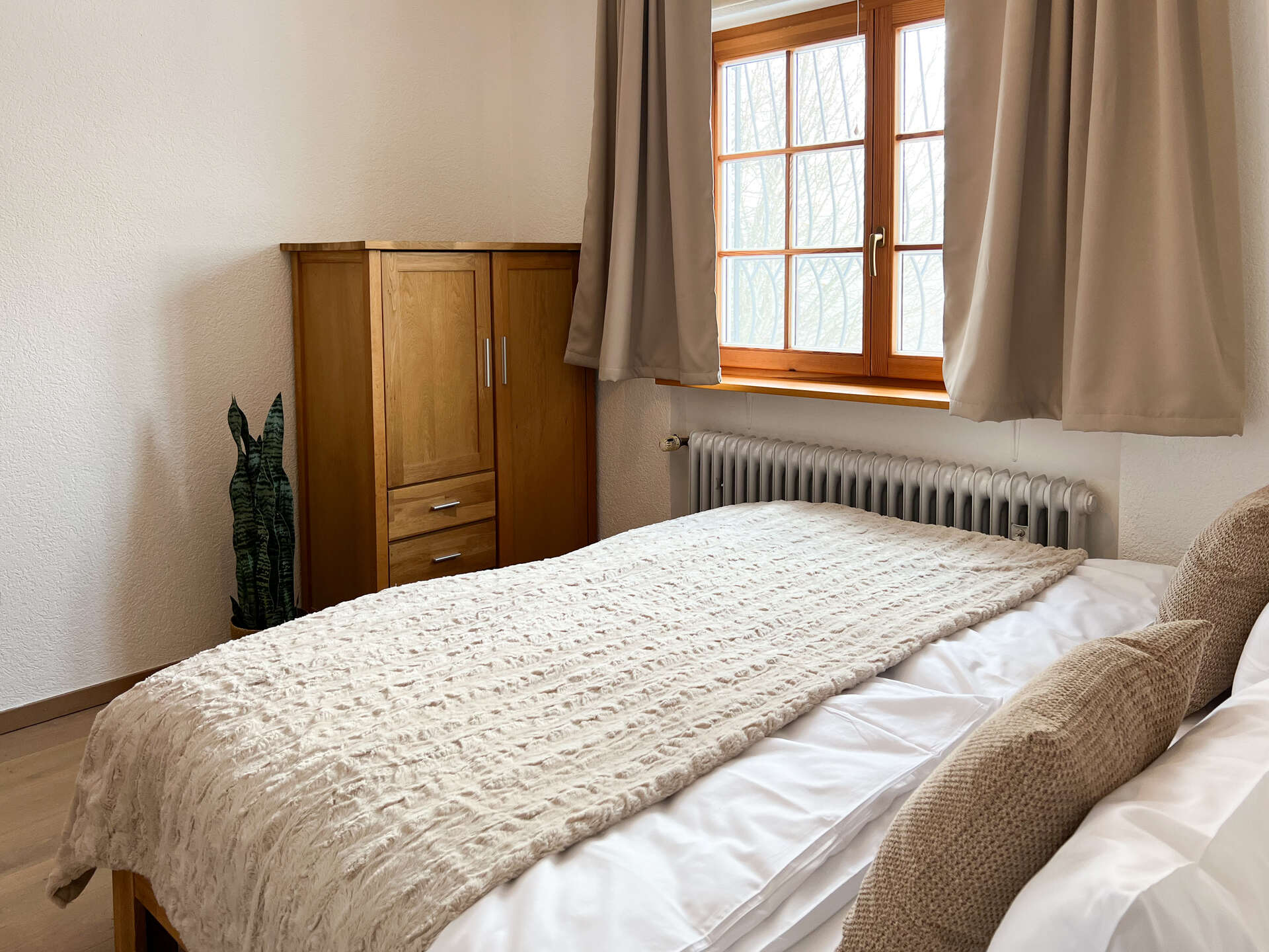 Gemachtes Bett im Schlafzimmer mit Tagesdecke und Kissen