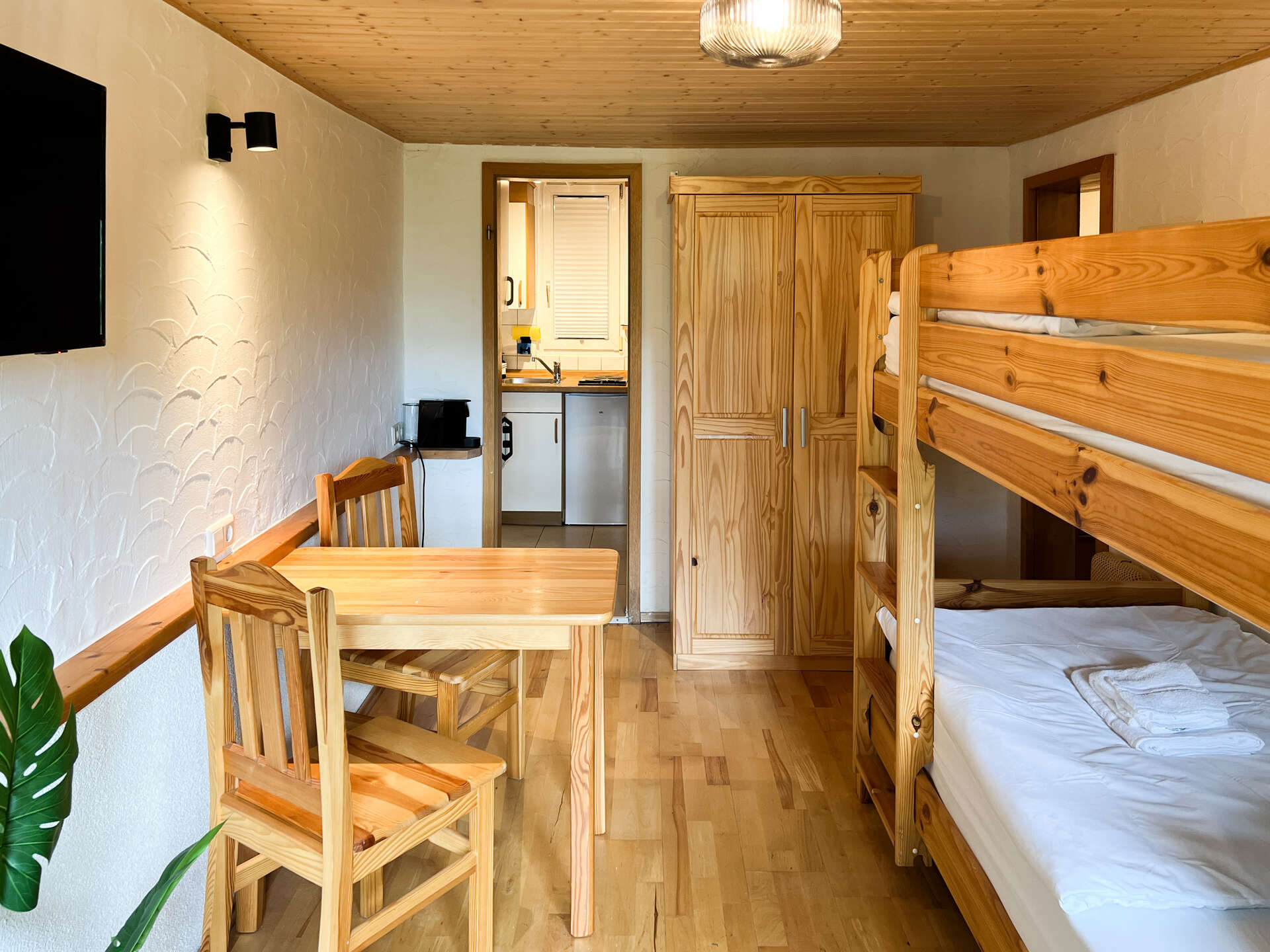 Blick in das Schlafzimmer mit Stockbett, Kleiderschrank und Zugang zur Kueche