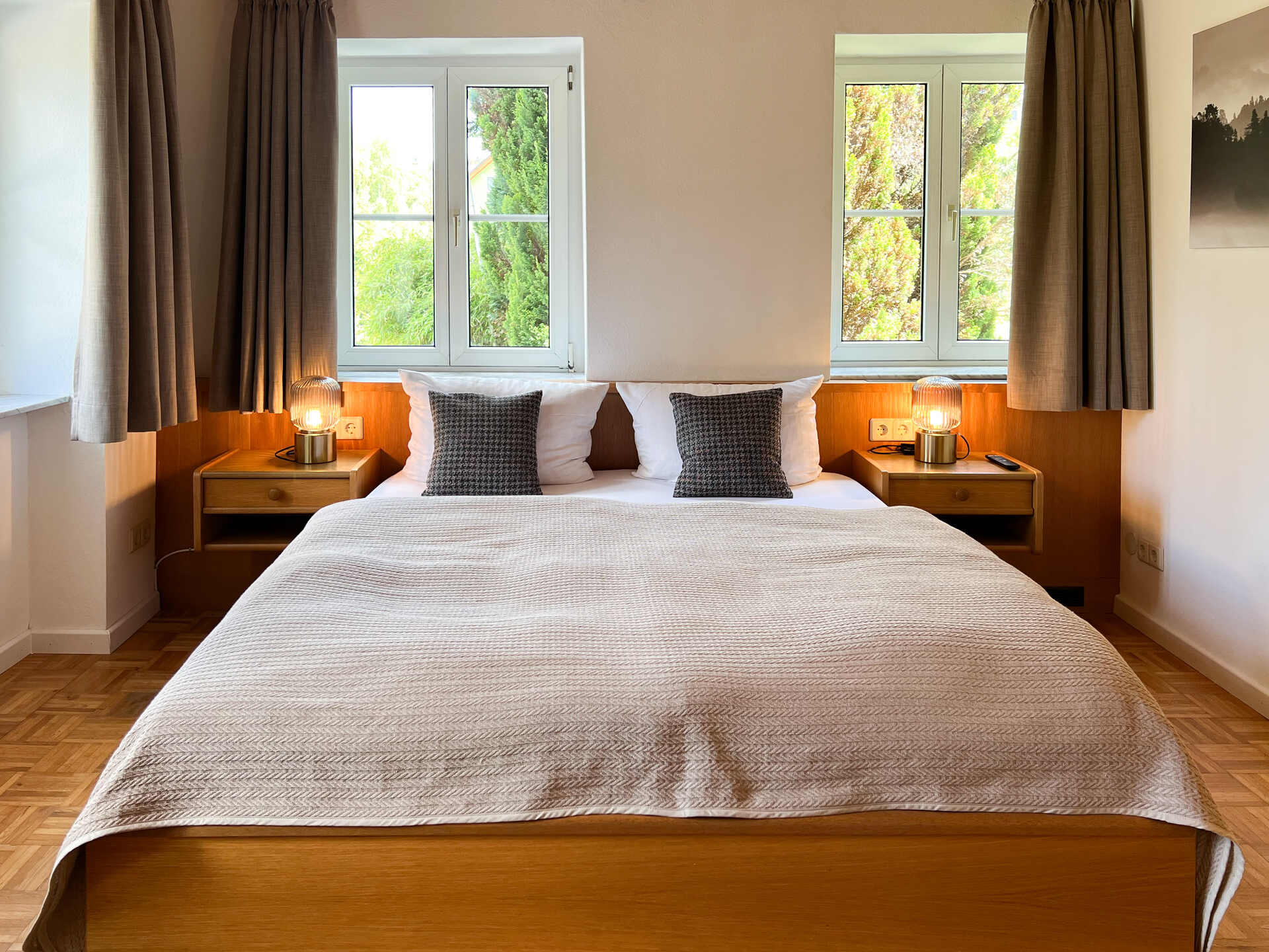 Doppelbett zwischen zwei Fenstern mit Nachttischen