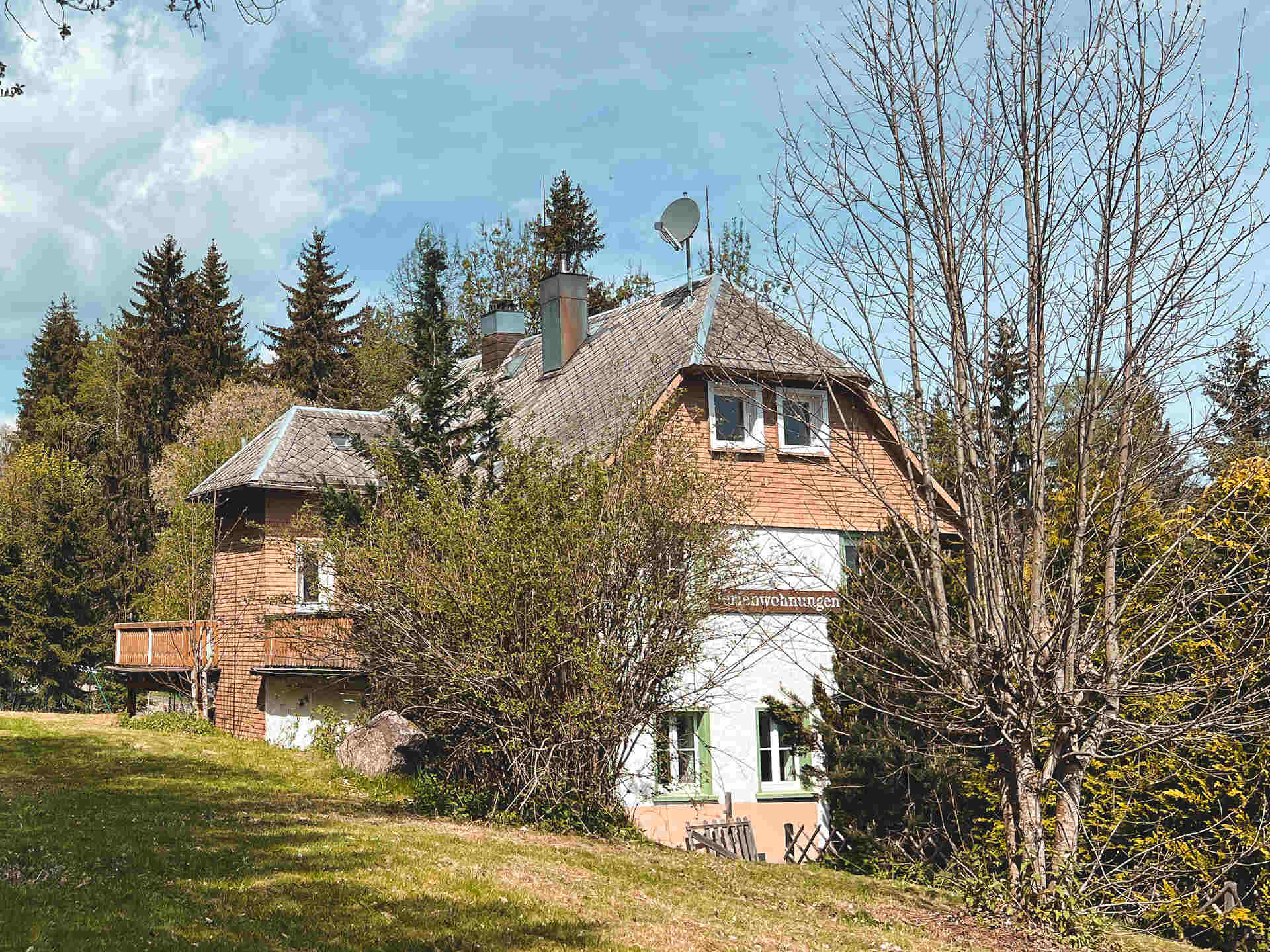 Haus im Schnee mit verschneiten Tannen Aussenansicht des Ferienhauses 'Haus Tanneck' im Sommer, umgeben von Baeumen und Gruenflaeche