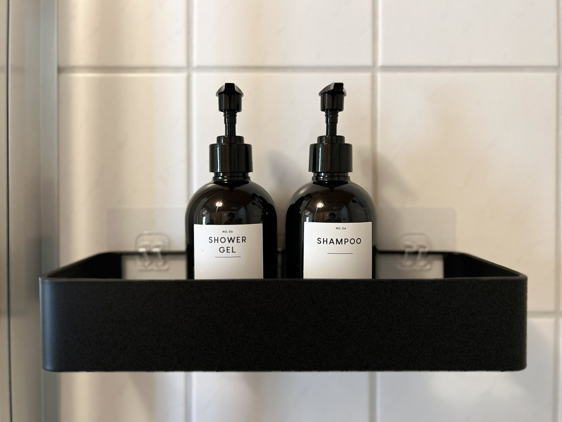 Shampoo und Duschgel in schwarzen Spendern in der Dusche