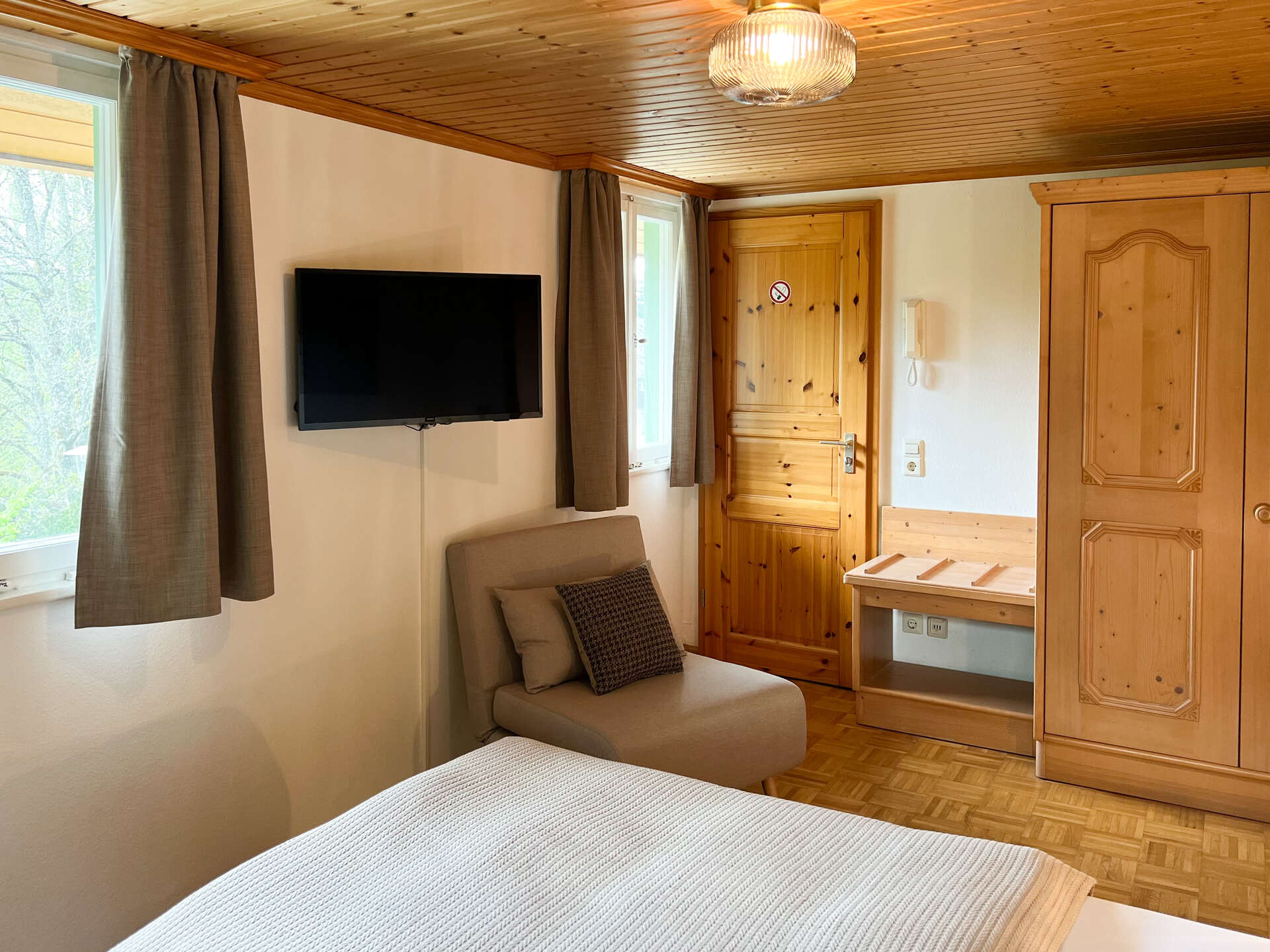 Gemuetliches Schlafzimmer mit Fernseher, Sessel und Kleiderschrank aus Holz