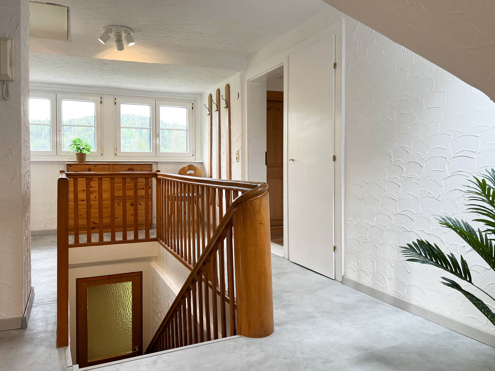Treppenhaus mit Fensterfront und Holzmoebeln