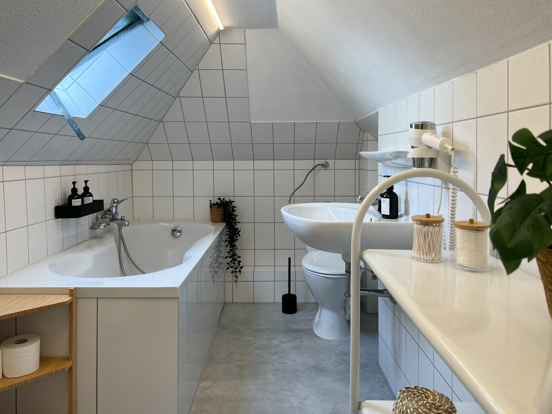 Eingangsbereich mit Treppe und Holzhaustuer Bad mit Dachschraege, Wanne und Waschbecken