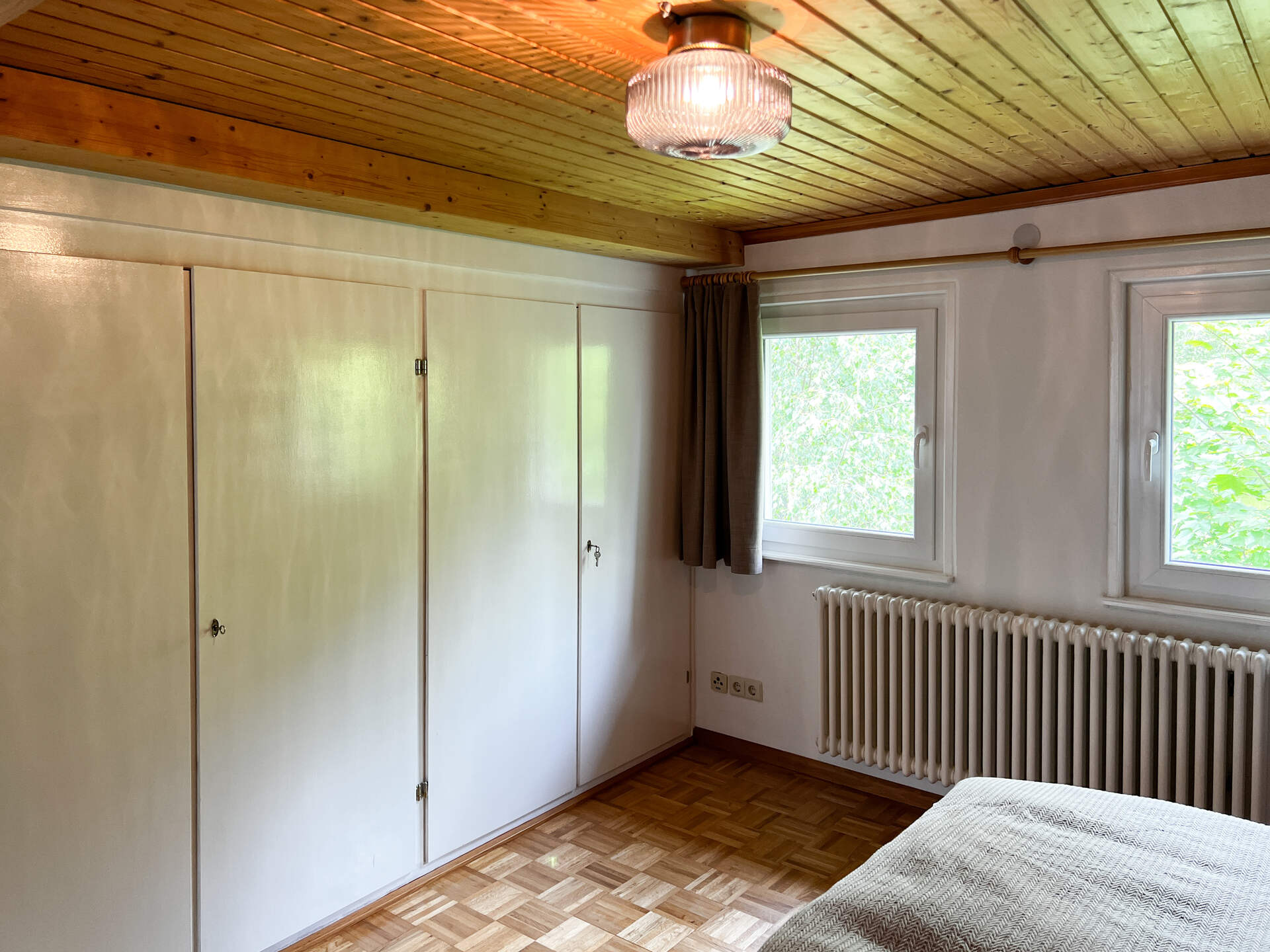 Schlafzimmer mit Einbauschrank und zwei Fenstern