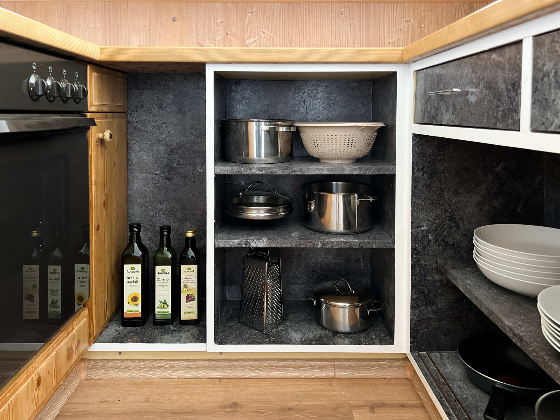 Kuechenschrank mit Toepfen, oelflaschen und Geschirr